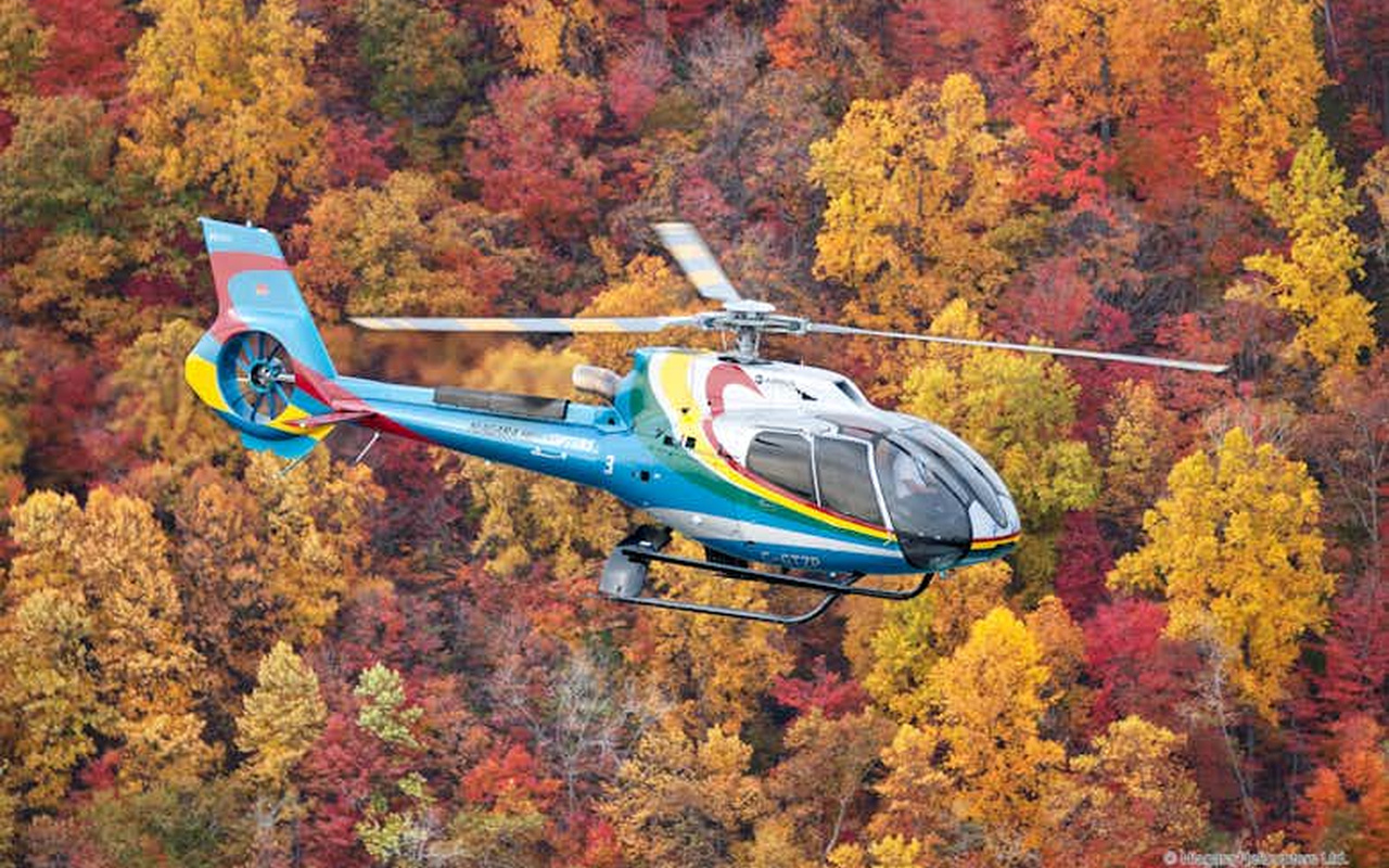 Marvel at the vibrant autumn colors of the surrounding landscape during a scenic seasonal flight