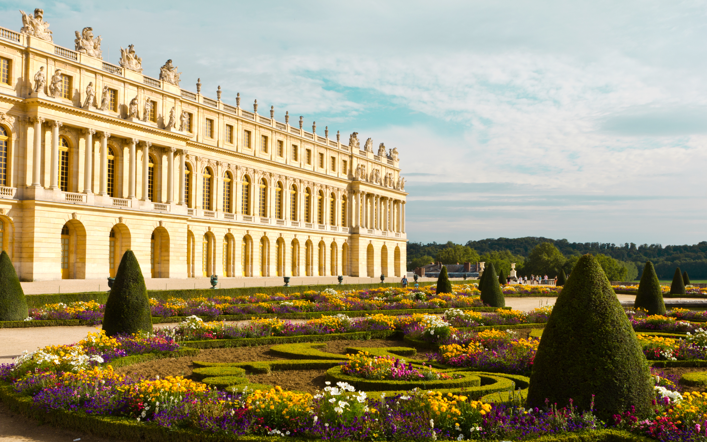 The grand facade of the Palace of Versailles glowing in golden sunset light