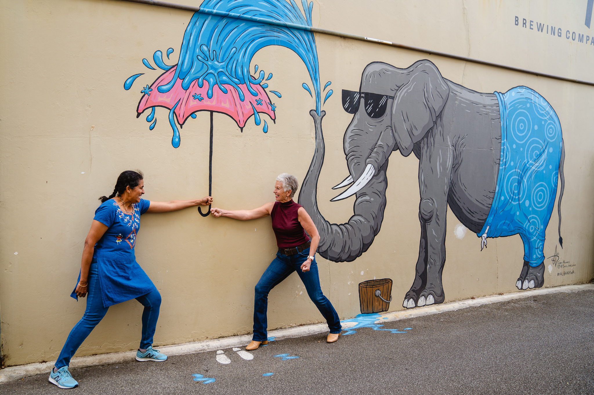 兩位女性在繪有大象的壁畫前擺拍。
