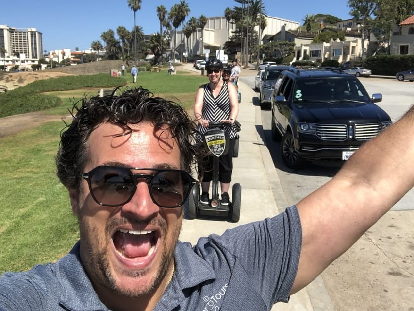Riders posing on Segways in front of colorful boutique shops in The Village