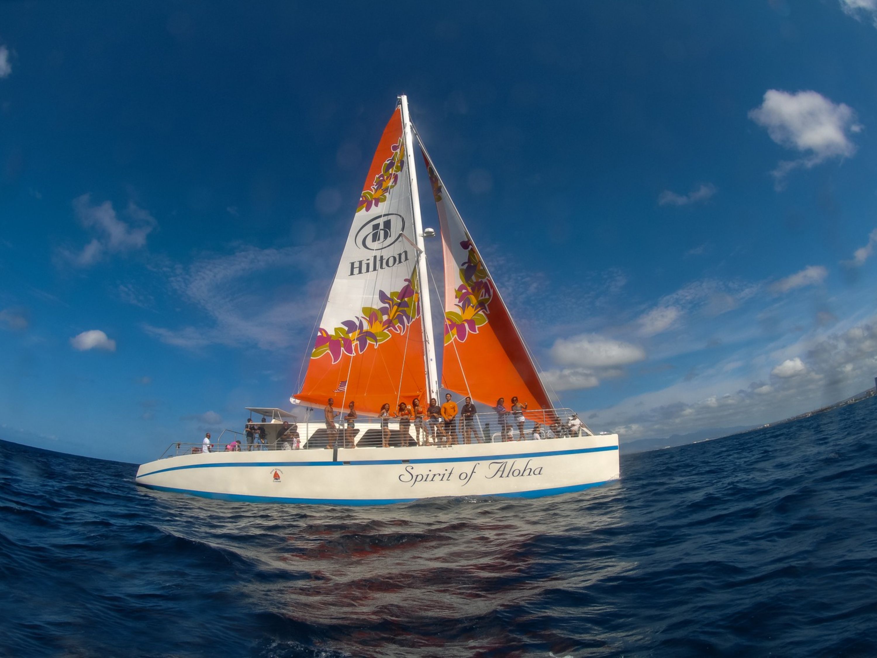 The catamaran sails gracefully across turquoise waters with Diamond Head in view