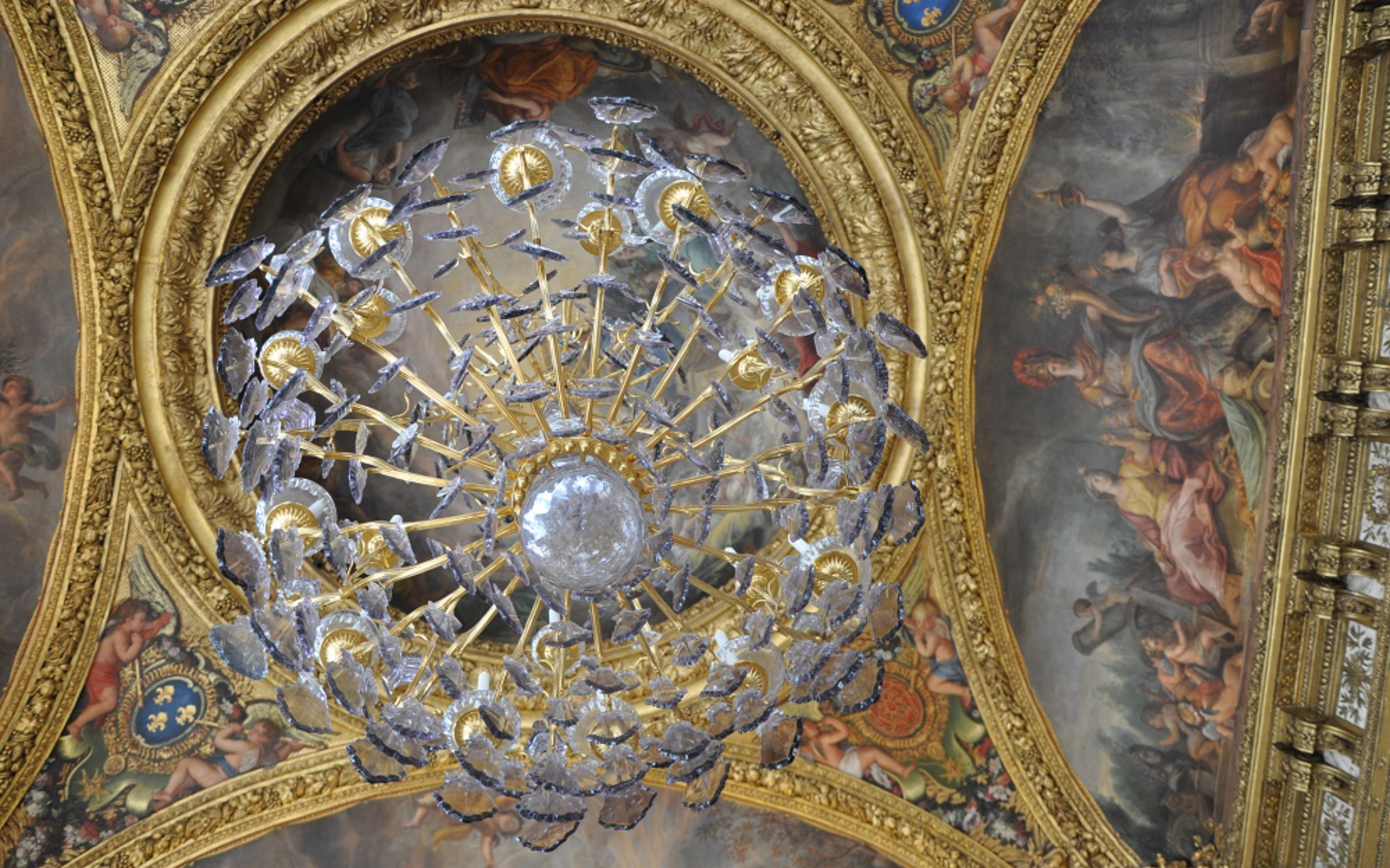 Golden statues and crystal chandeliers lining the Hall of Mirrors