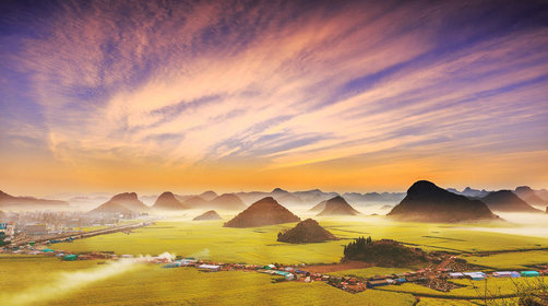 世界級規模：羅平擁有近百萬畝的油菜花田，被吉尼斯世界紀錄認證為“世界最大的自然天成花園”。其規模之宏大，色彩之絢爛，在全球範圍內都屬罕見。

獨特的喀斯特地貌背景：與平原地區的花海不同，羅平的油菜花盛開在典型的喀斯特峰林之間。金雞峰叢的錐形山丘如棋子般散落在金色海洋中，形成了“海上桂林”般的奇幻景觀，層次感極強。

絕佳的攝影主題：

全景：站在金雞峰叢觀景臺，日出時分雲霧繚繞，峰林在花海中若隱若現，是經典的“天堂明信片”畫面。

曲線：牛街螺絲田的油菜花沿著梯田的螺旋轉彎種植，形成極富韻律感的金色曲線，