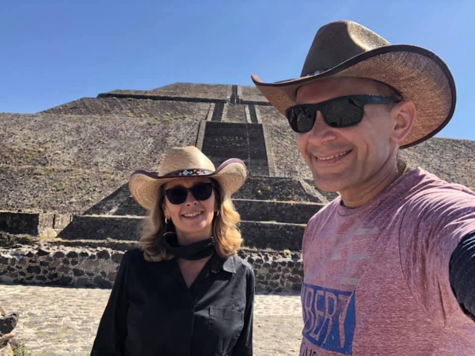 Happy travelers posing with wide smiles in front of Teotihuacan’s Pyramid of the Sun