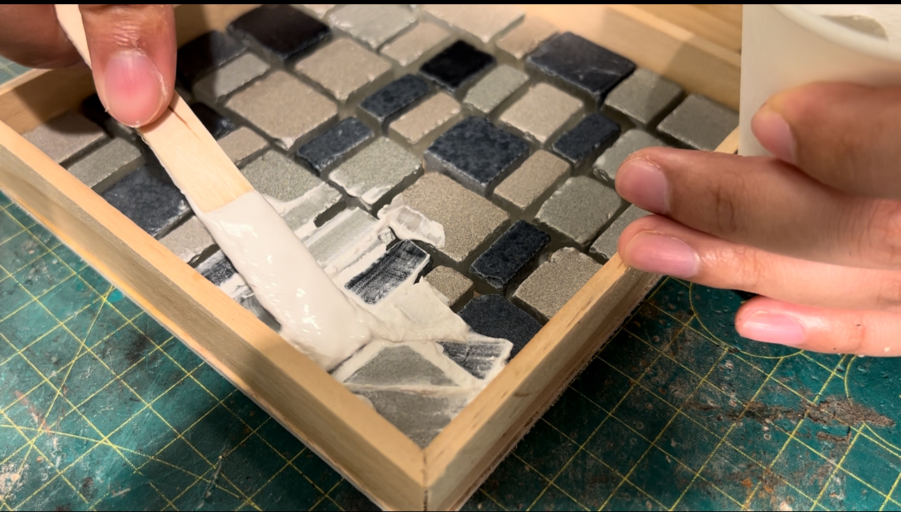 將灌漿均勻地塗抹在馬賽克托盤上，填充每塊瓷磚之間的空隙