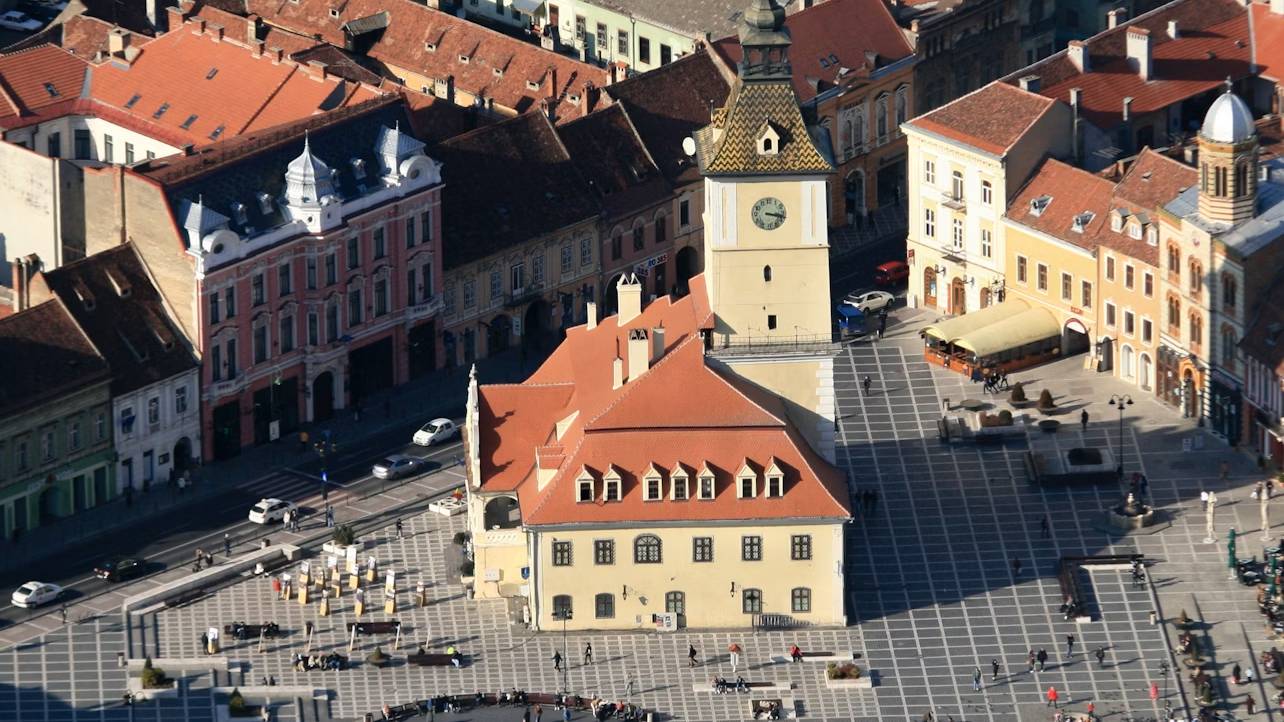 Stroll through cobblestone streets with colorful medieval buildings in Brasov’s historic center