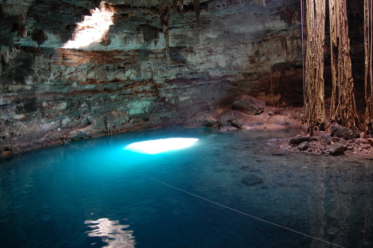 A view of the clear, glistening waters of a cenote with tranquil surroundings