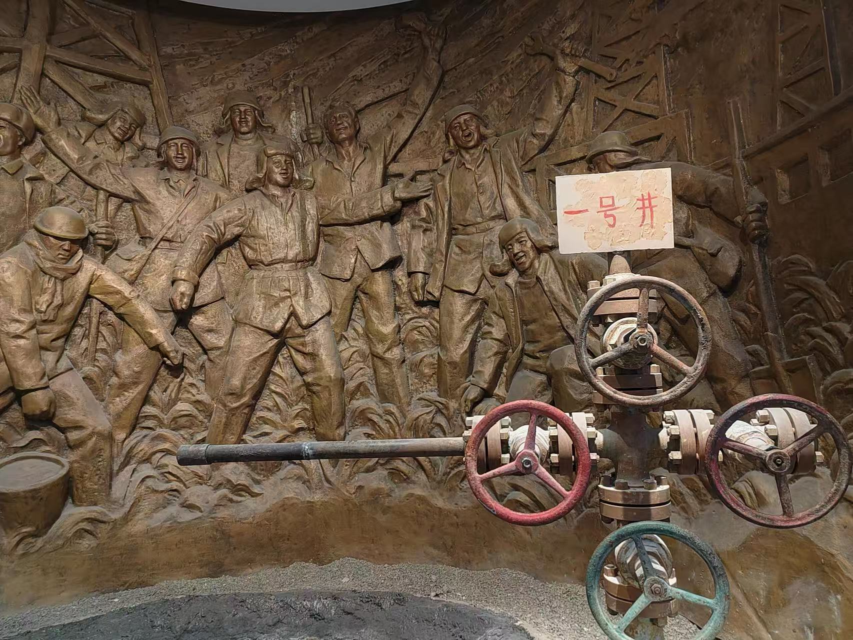 一號井主題青銅浮雕，刻畫石油工人歡呼勞作的昂揚姿態，前景擺放真實老舊採油閥門管線。浮雕還原開採出油時激動的場面，重現油田開發光輝歷史，感受老一輩建設者的熱血與榮光