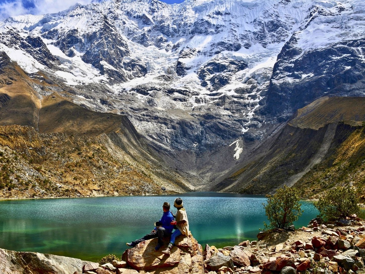 Witness the mesmerizing colors of the glacial lake shimmering beneath snow-capped peaks