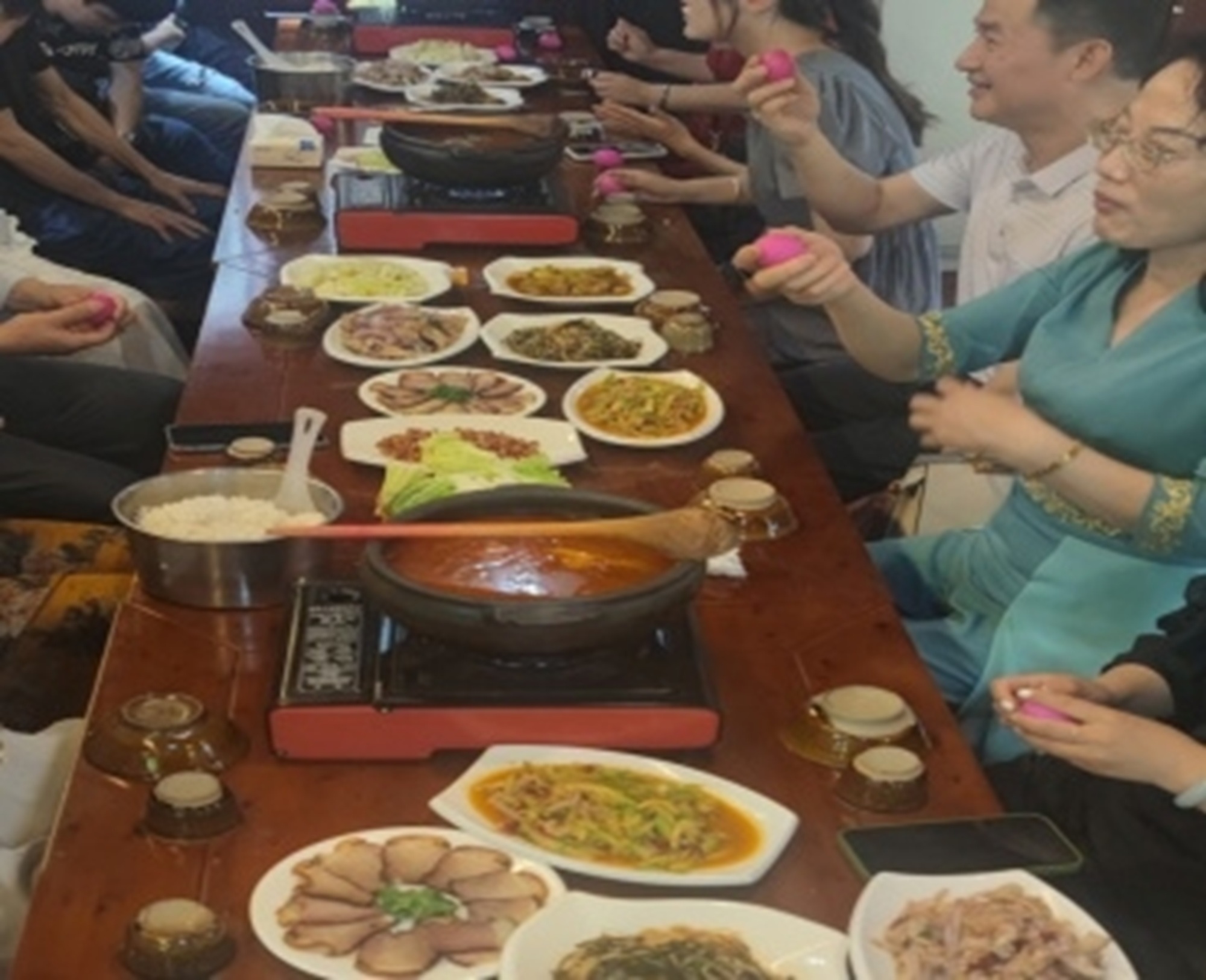 長桌之上佳餚琳琅,眾人圍坐笑語晏晏,手中彩球點亮相聚時光,滿溢溫馨與歡樂 長桌之上佳餚琳琅,眾人圍坐笑語晏晏,手中彩球點亮相聚時光,滿溢溫馨與歡樂