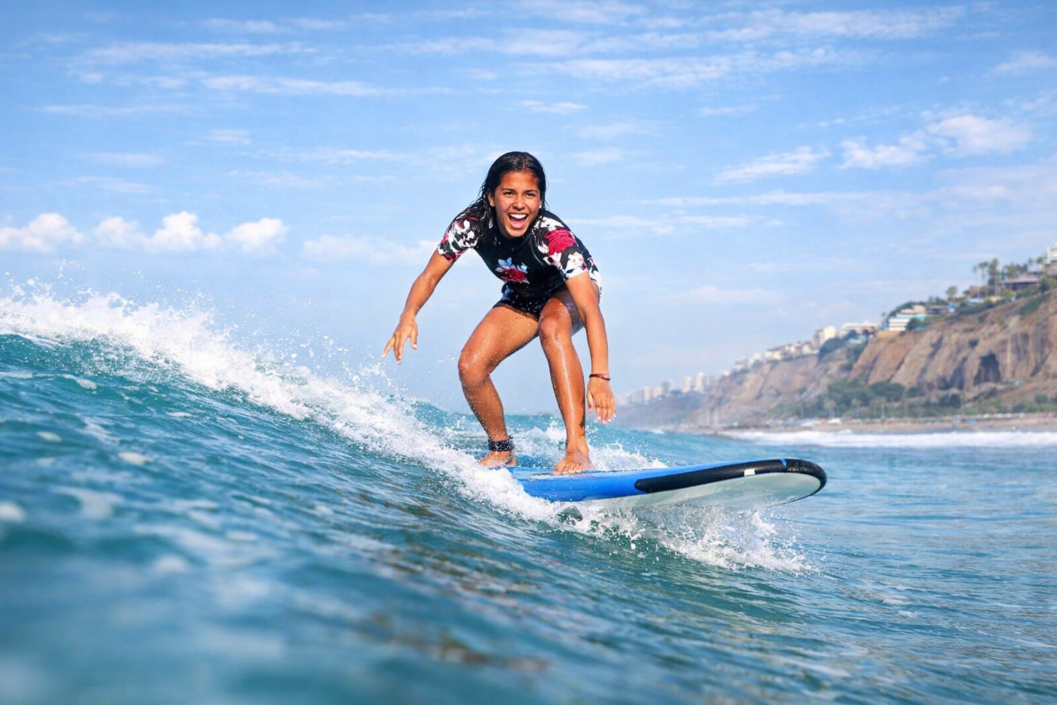 Beginner surfer smiling while balancing on the board, showing how accessible and fun the lesson is for first-timers.