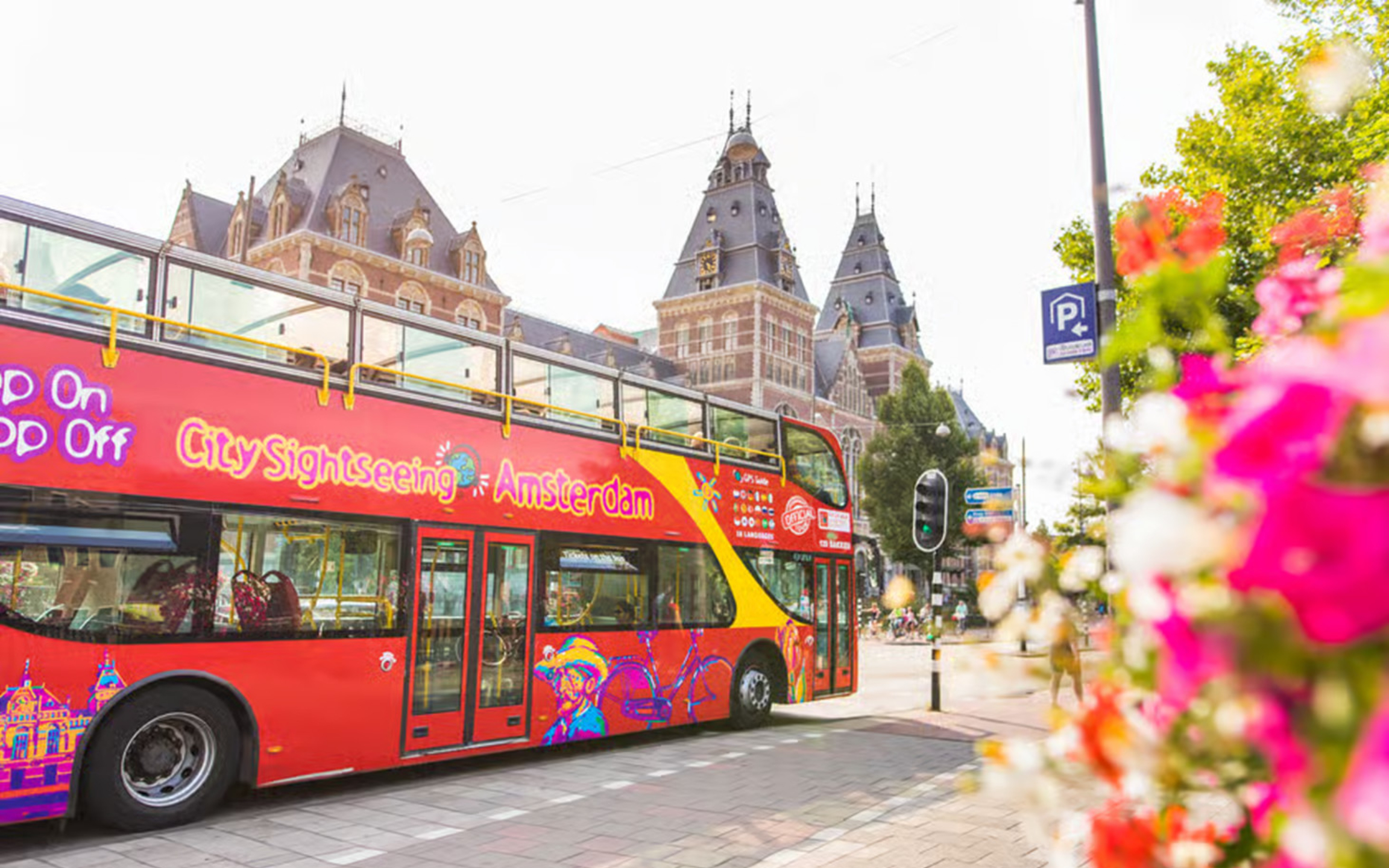 A red hop-on hop-off bus passing Amsterdam landmarks, offering flexible sightseeing around town