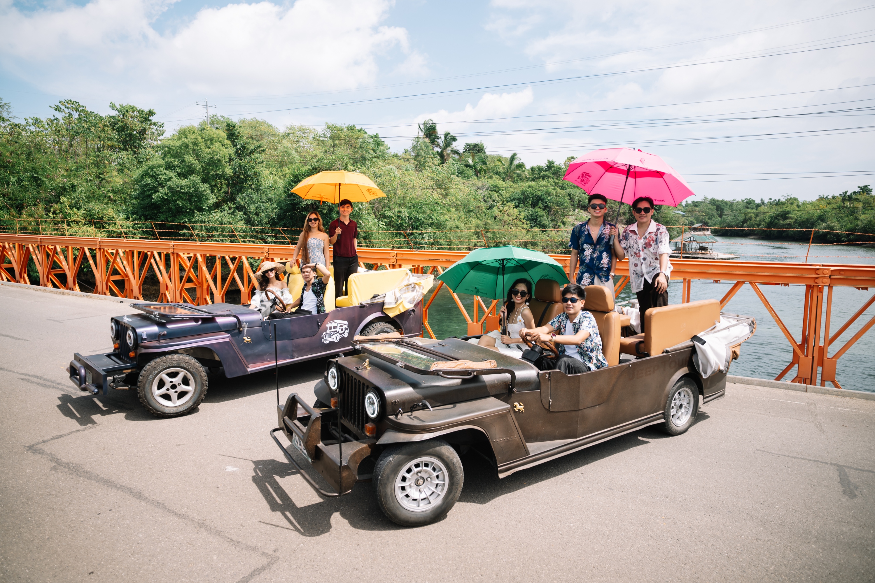 Two groups parked with their jeeps while people hold umbrellas to protect from the sun
