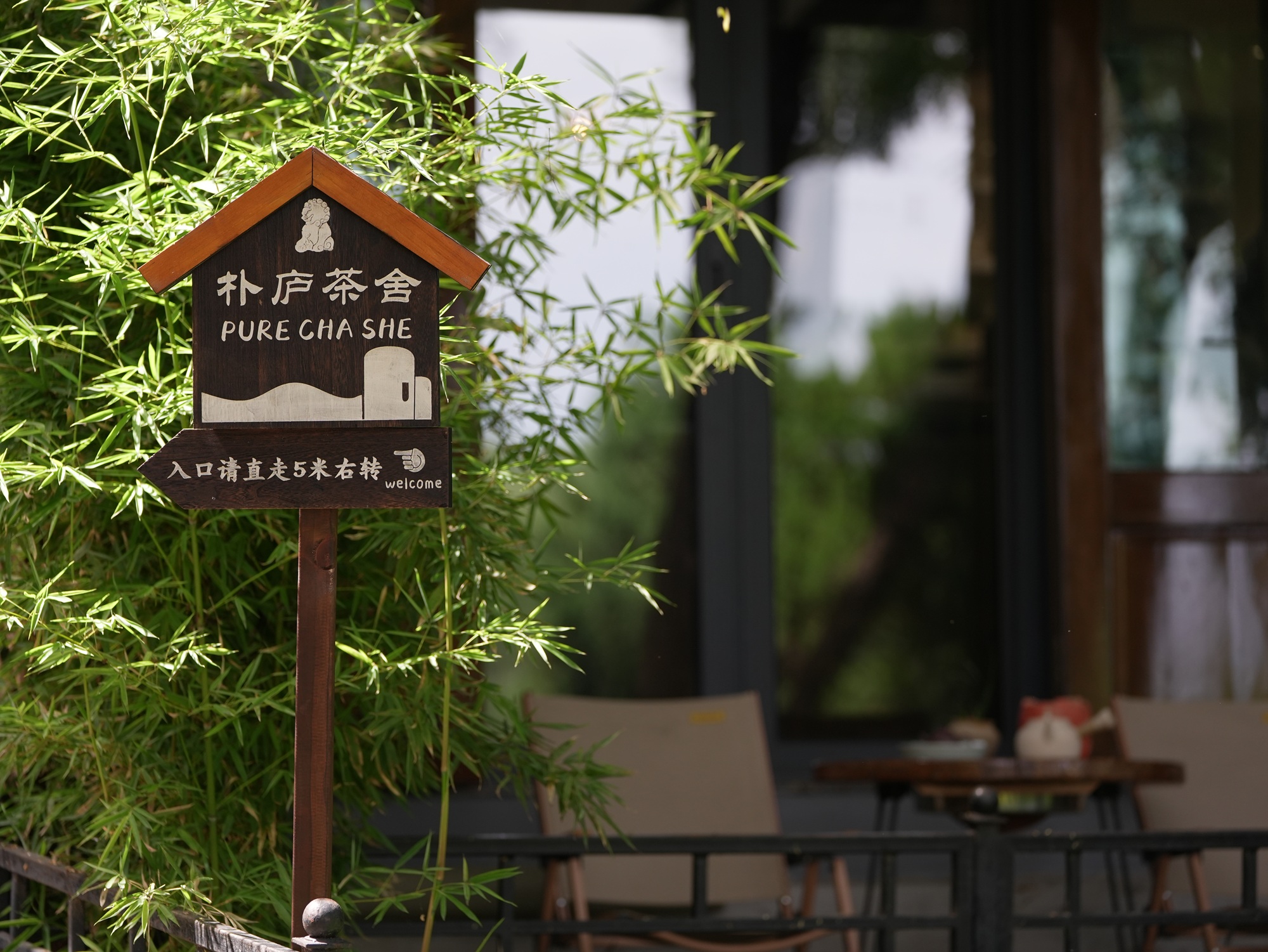 樸廬茶舍指示牌，隱於綠意中，指引你踏入一方茶韻天地