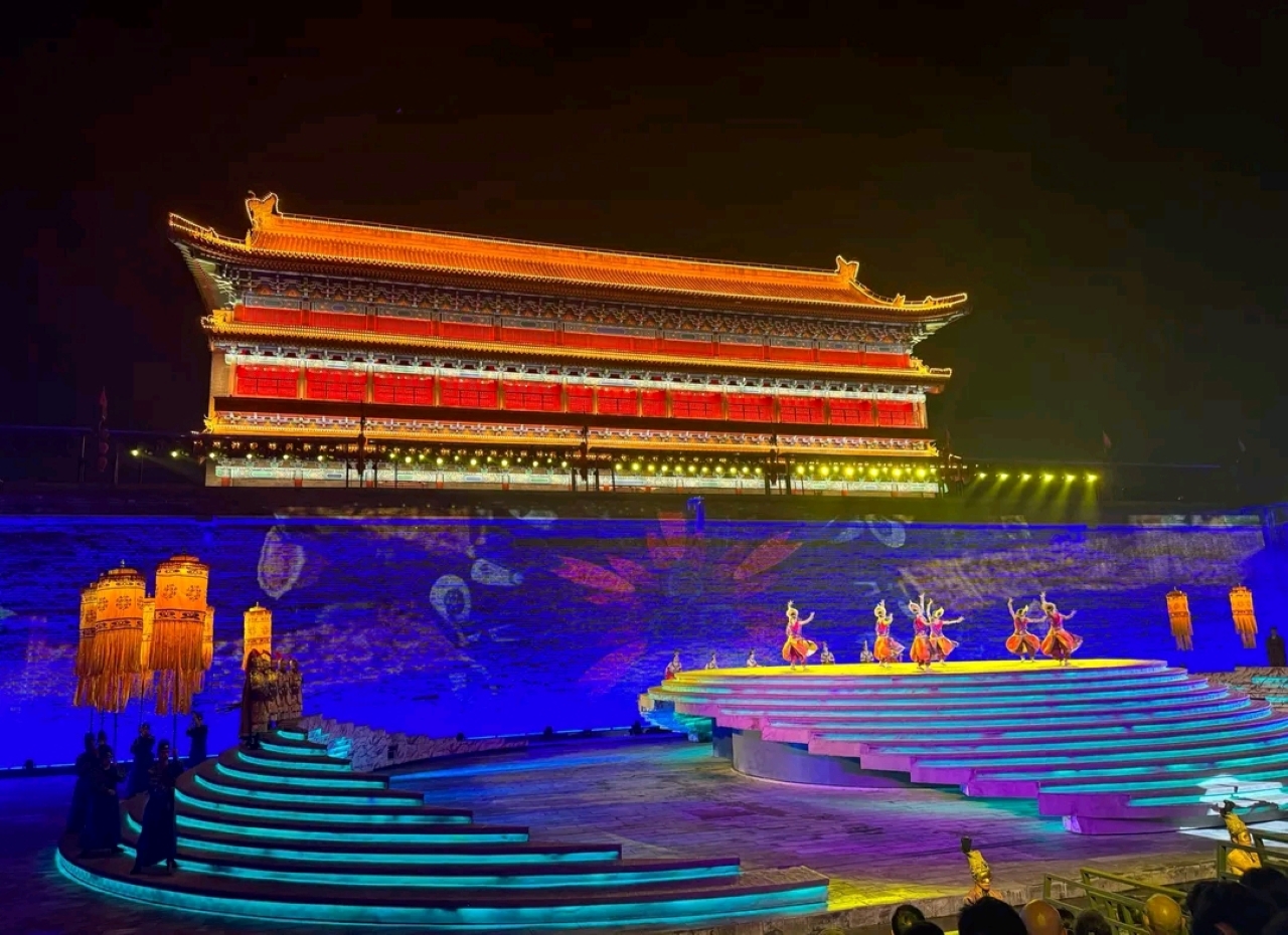 舞臺上，一群舞者翩翩起舞，她們的服飾色彩鮮豔，動作整齊優美