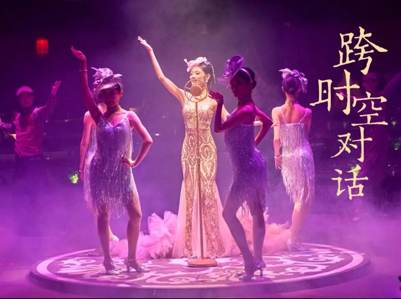 舞臺中央，主表演者身著鎏金暗紋長裙，立於復古麥克風前，氣質優雅如老上海歌舞廳的歌女；周圍伴舞演員穿綴滿流蘇的紫調亮片短裙，搭配同色系禮帽，身姿搖曳間流蘇隨動作輕晃，滿是復古爵士風情。