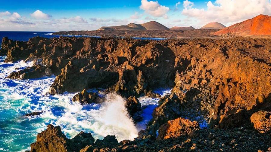 Admire the dramatic volcanic cliffs of Los Hervideros, where waves crash against ancient lava formations