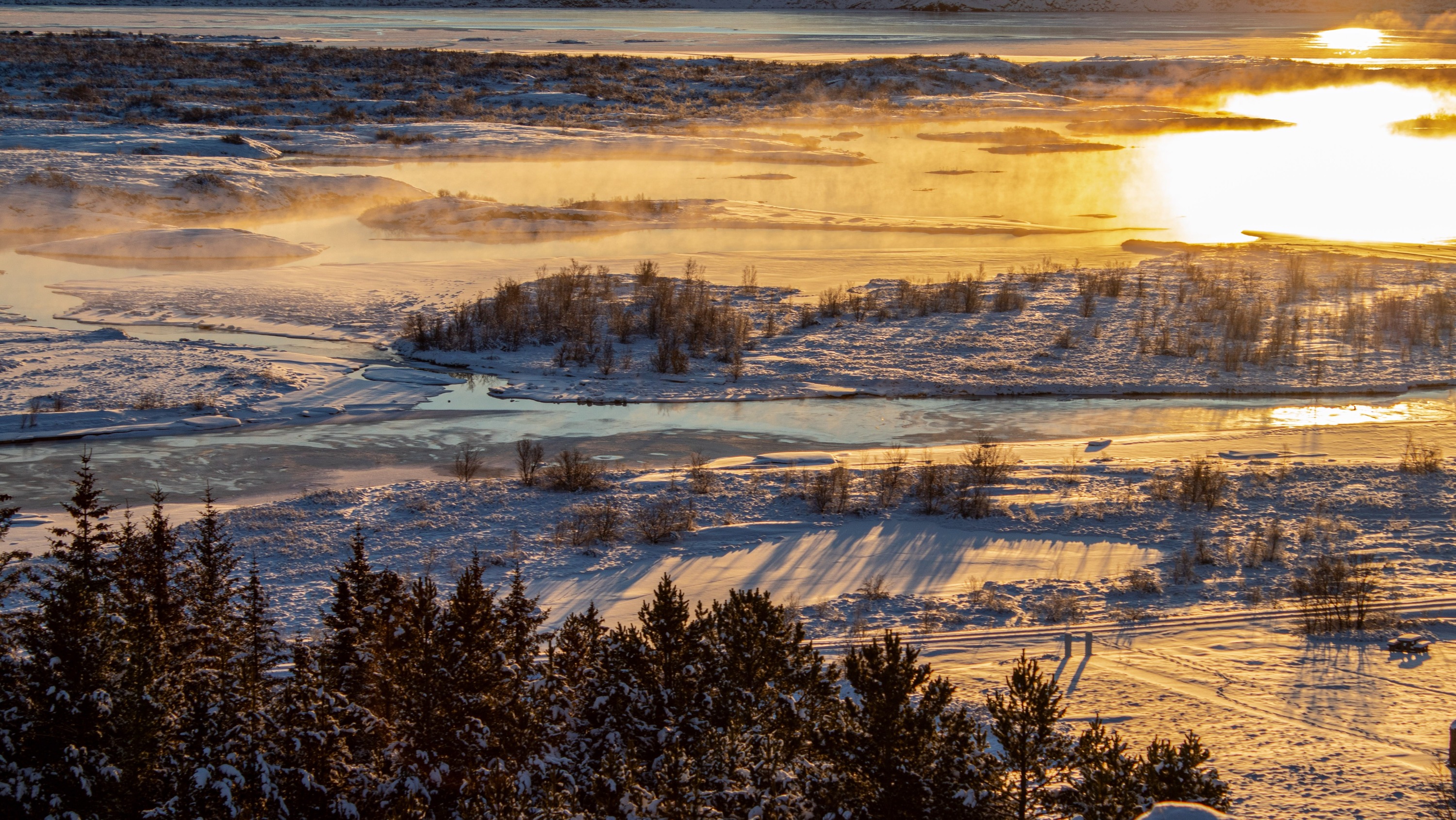 Witness the Golden Circle at sunrise, where a warm morning glow illuminates the icy winter landscape