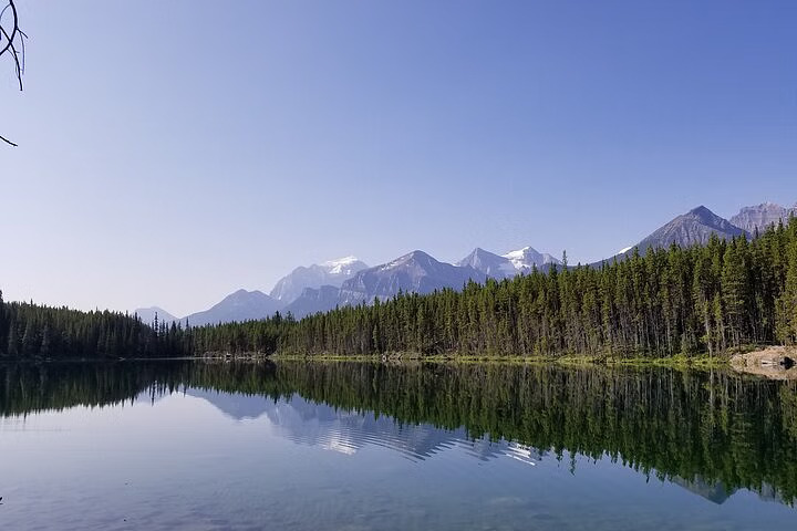 Admire mirror-like calm waters reflecting snow-capped peaks along scenic Icefields Parkway roadside