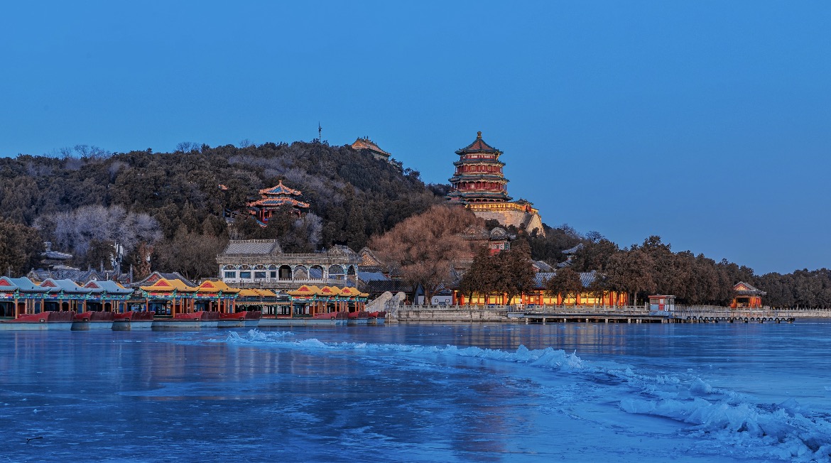 冬日薄暮，冰封的昆明湖倒映著燈火璀璨的佛香閣與湖畔五彩的亭臺，為頤和園暈染出一片靜謐而夢幻的流光。