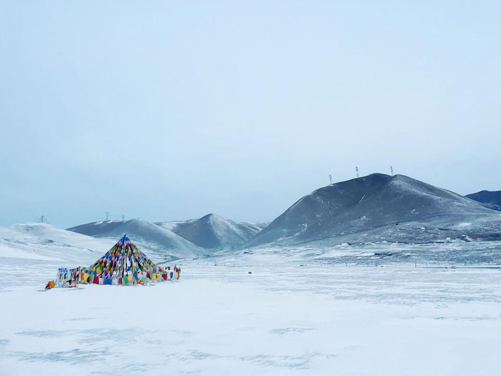 蒼茫雪原綿延向遠山，五彩經幡靜靜佇立，在素白天地間格外醒目，高原清冷遼闊，藏著靜謐虔誠的氛圍感