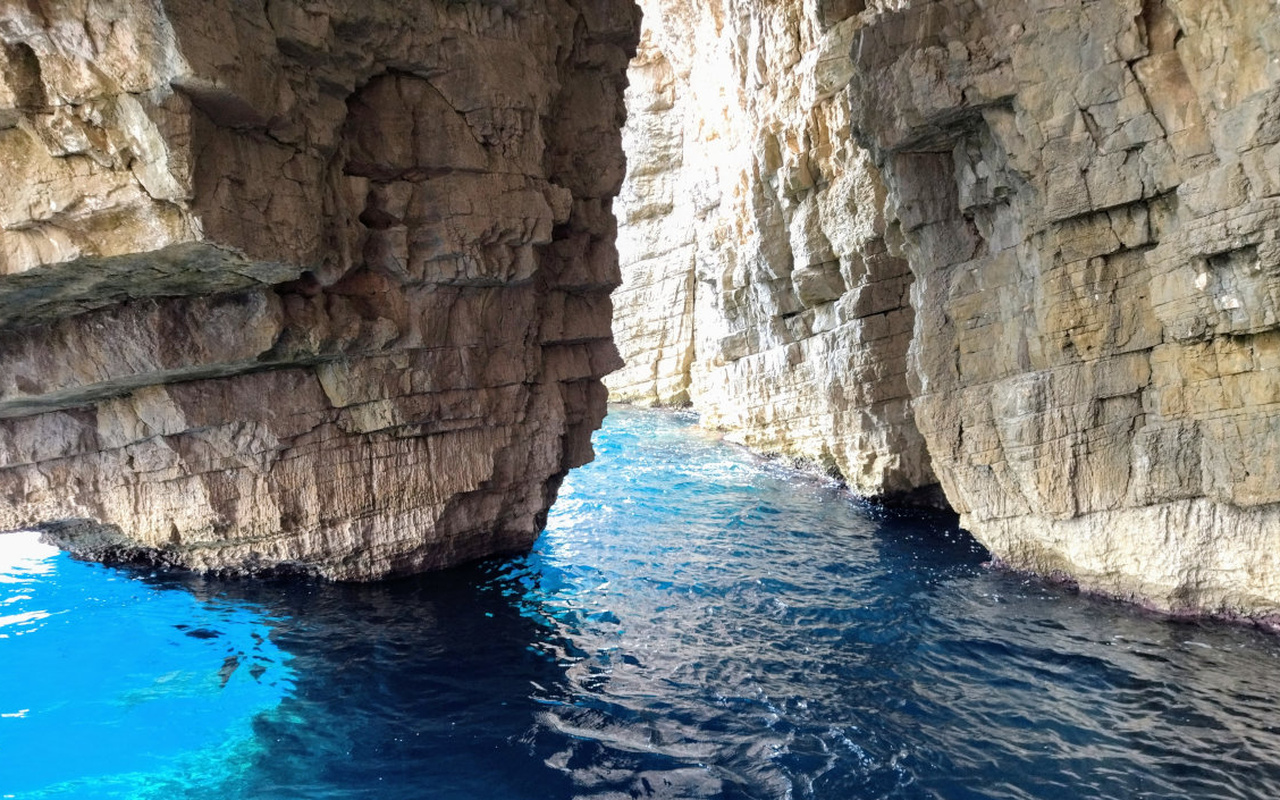 Cruise into a stunning sea cave with turquoise waters and towering cliffs