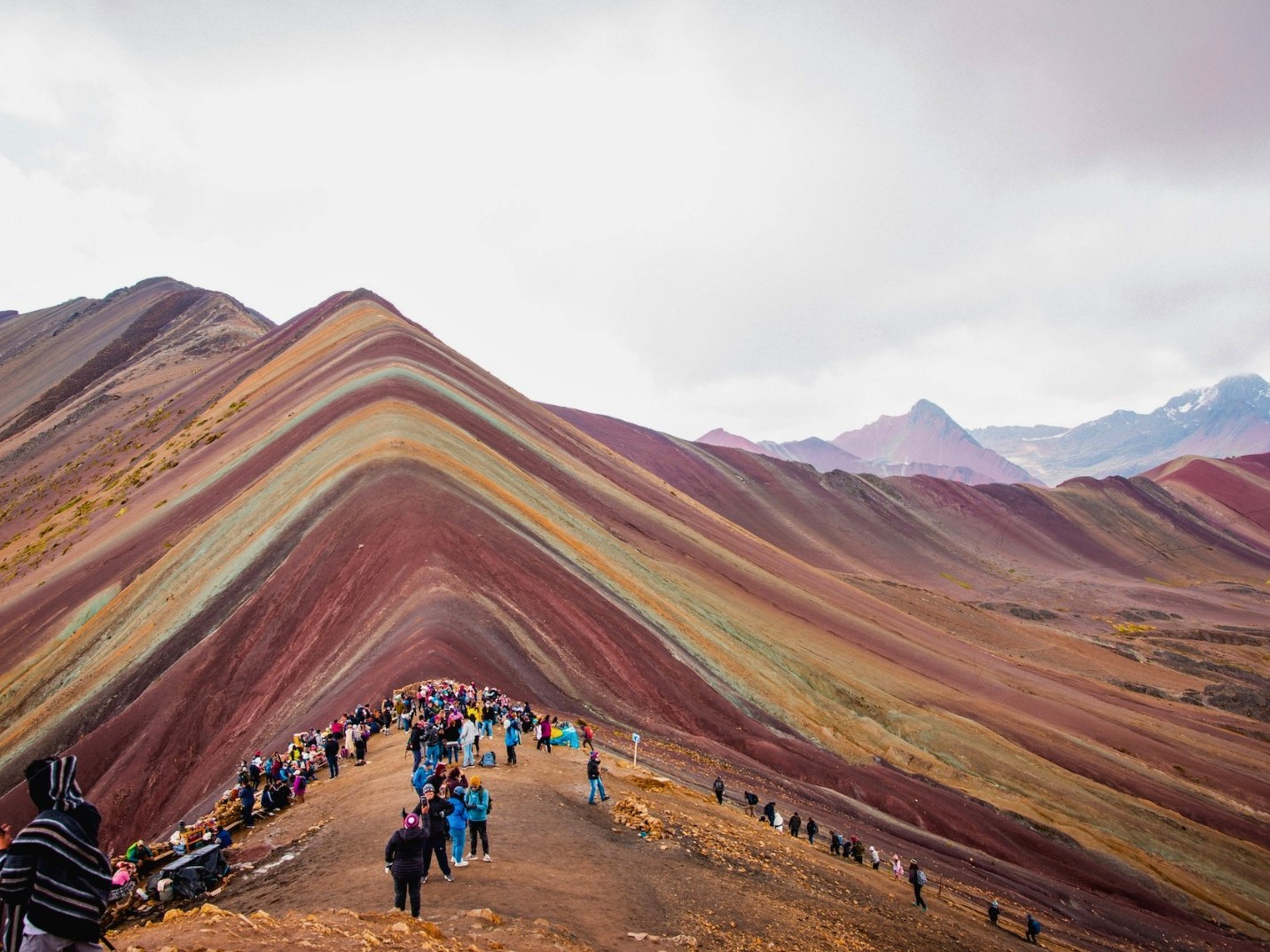Trekkers follow the colorful mountain ridge as they steadily approach the towering summit