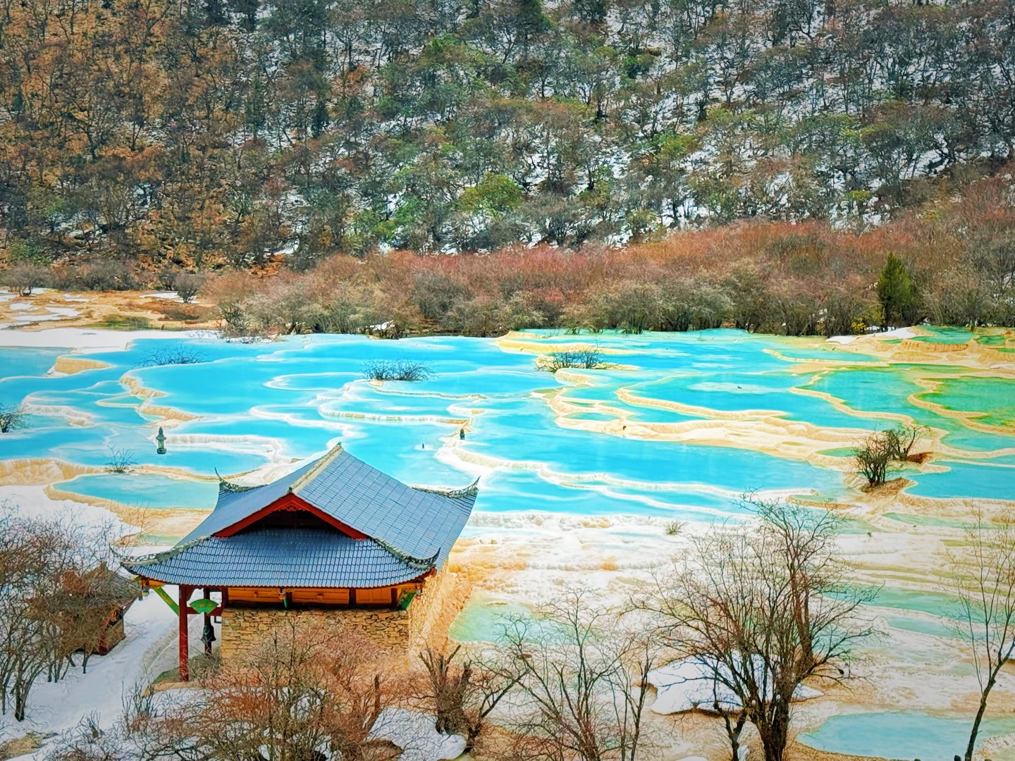 黃龍古寺靜靜佇立在鈣華彩池邊，藏漢交融的建築背靠雪山，藍黃相間的彩池如瑤池落人間，冰雪初融時，這裡仙氣氤氳，盡顯高原秘境的神聖與靜謐