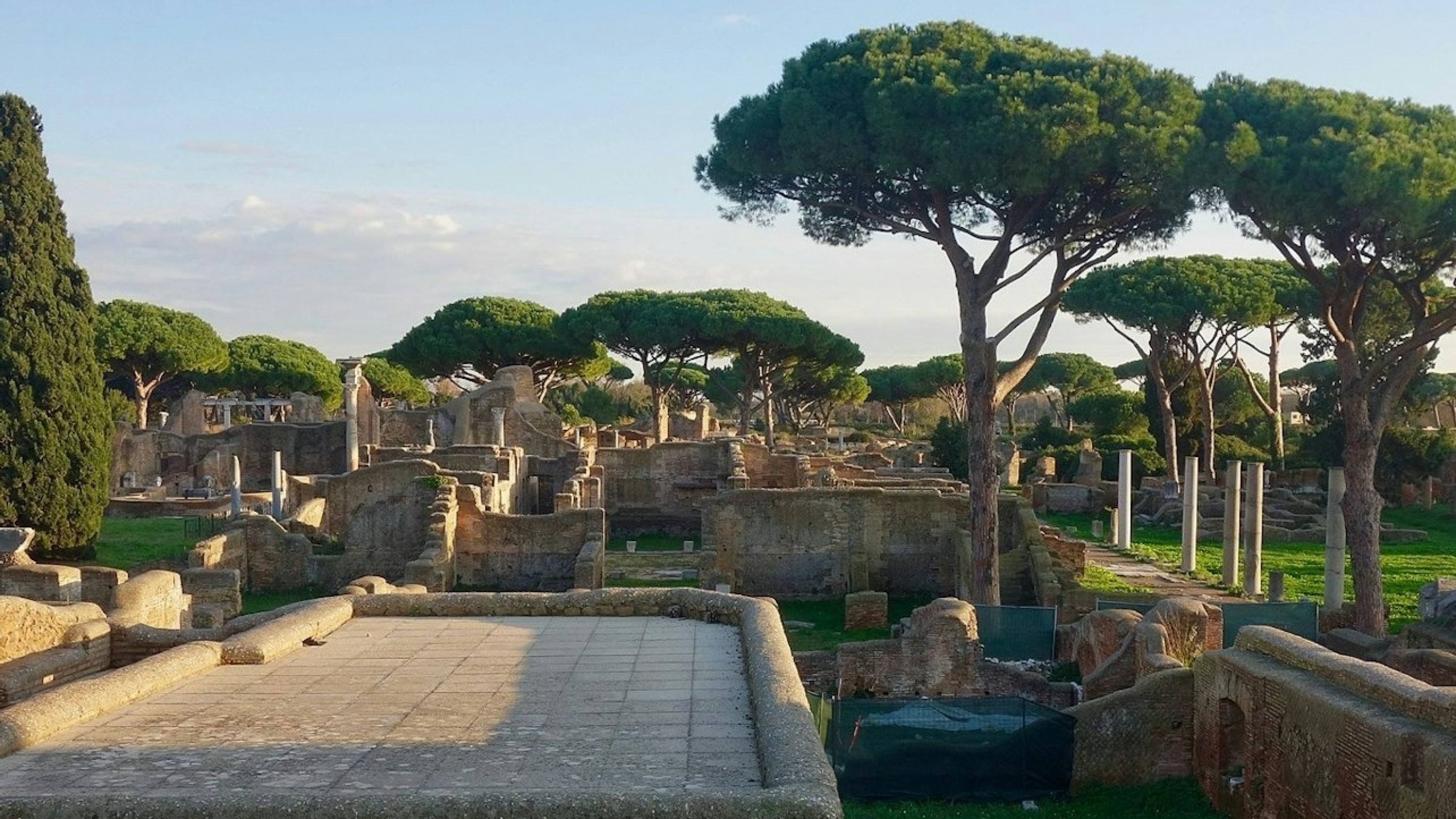 Panoramic view of ancient Ostia ruins surrounded by lush greenery under blue skies