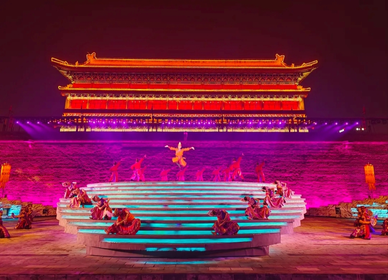 舞臺上，一名舞者高高躍起，動作輕盈矯健，周圍是身著傳統服飾的舞者