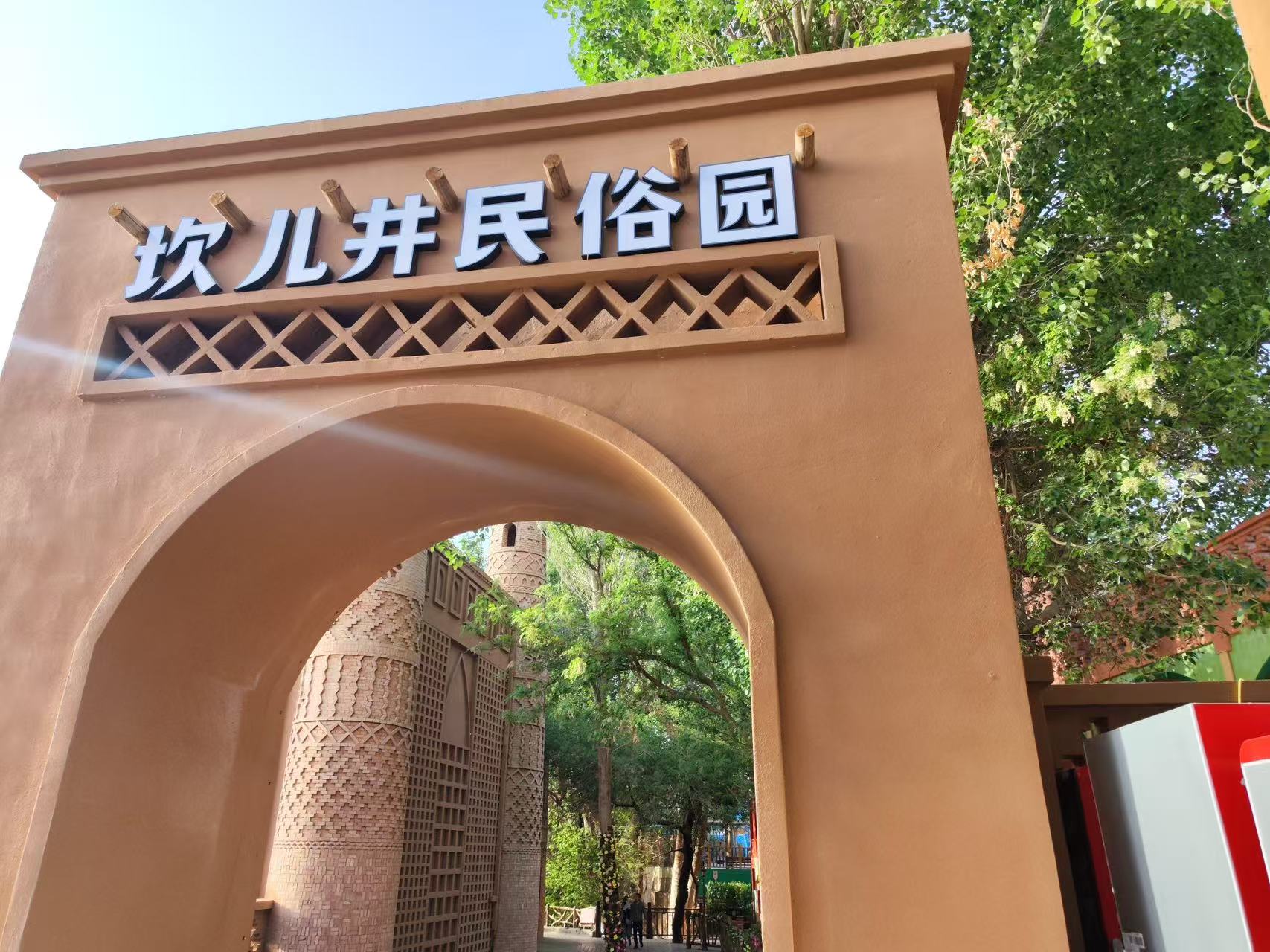 土棕色拱門式門樓醒目刻著 “坎兒井民俗園”,搭配維吾爾特色菱格鏤空雕花,拱門後能看到特色夯土建築與蔥鬱綠樹,民俗風情濃郁,是園區正門入口 土棕色拱門式門樓醒目刻著 “坎兒井民俗園”,搭配維吾爾特色菱格鏤空雕花,拱門後能看到特色夯土建築與蔥鬱綠樹,民俗風情濃郁,是園區正門入口