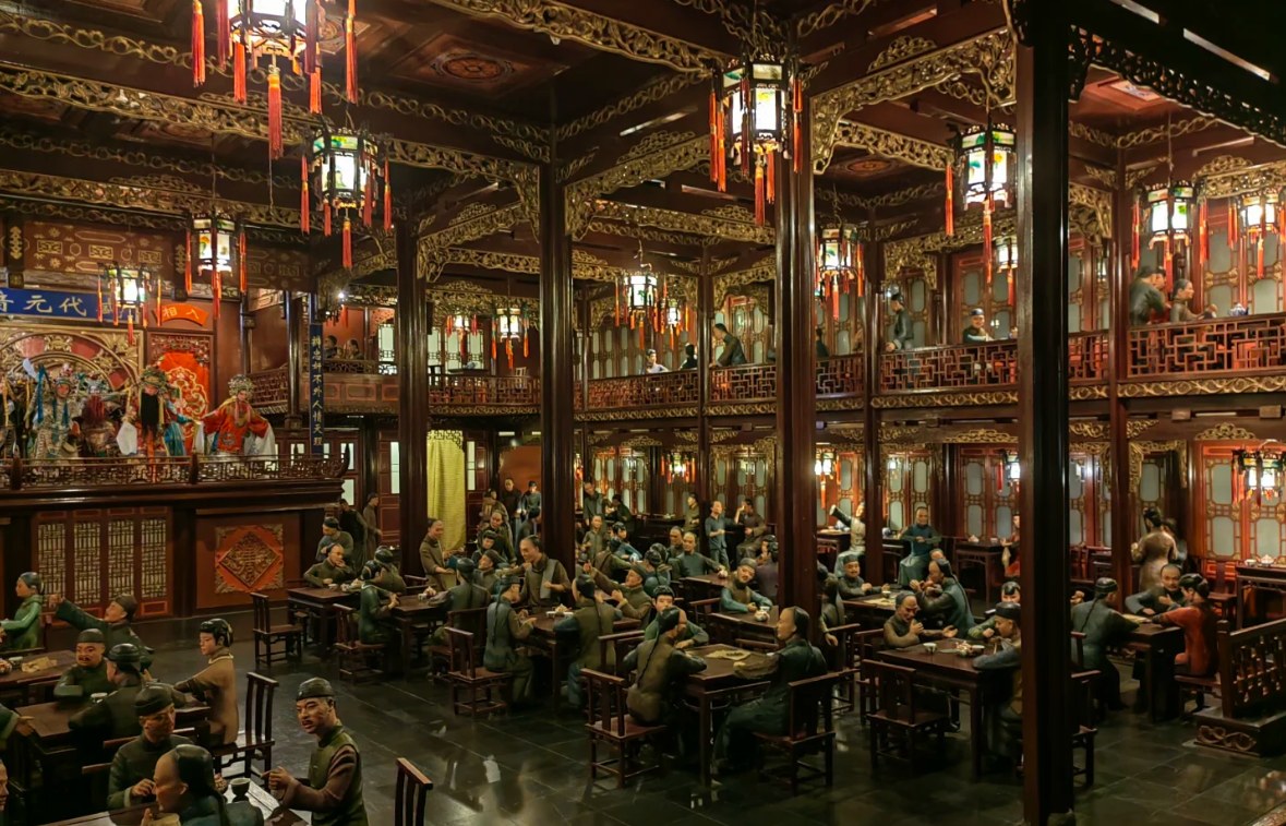 展館內復刻百年前滬上戲曲茶座，雕樑畫棟的木質結構精緻繁複，紅燈籠垂掛錯落有致。蠟像還原食客聽戲、交談的日常模樣，中式傳統戲臺與喧鬧茶客相映，盡顯老上海的民俗風情與文化底蘊