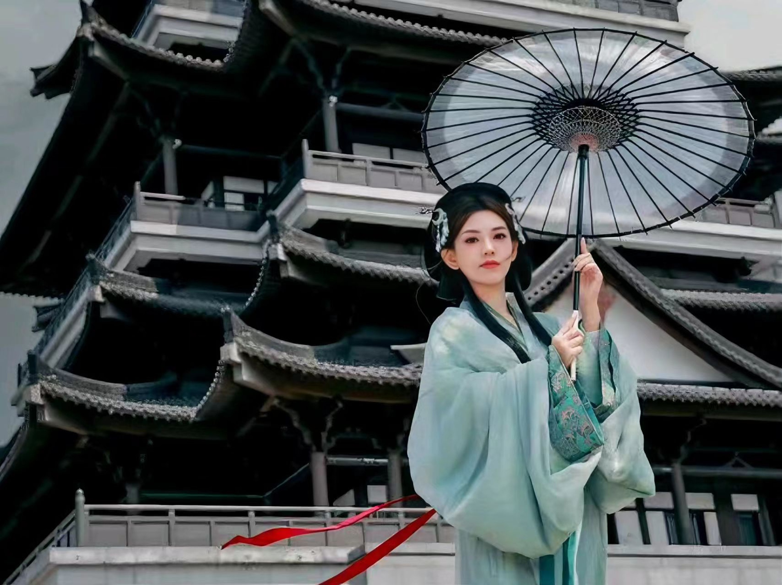 淺青漢服配玉簪髮飾,少女持黑傘立於樓閣前,紅綢飄曳,盡顯宋制漢服的清雅與飄逸 淺青漢服配玉簪髮飾,少女持黑傘立於樓閣前,紅綢飄曳,盡顯宋制漢服的清雅與飄逸