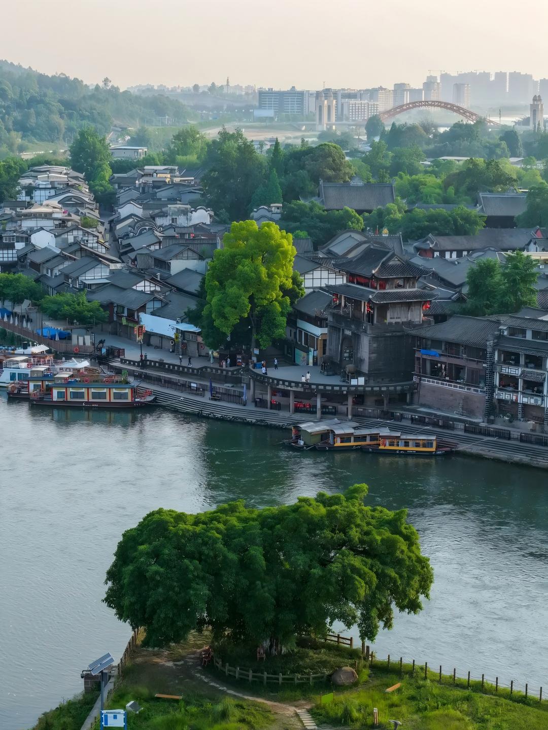 遠眺黃龍溪遠眺黃龍溪，錦江如帶環繞千年古鎮。青瓦連綿、飛簷錯落，廊橋臥波映碧水，古榕枝繁遮黛瓦，晨霧或晚霞中更顯靜謐悠遠，盡覽川西水鄉的靈秀與古韻。