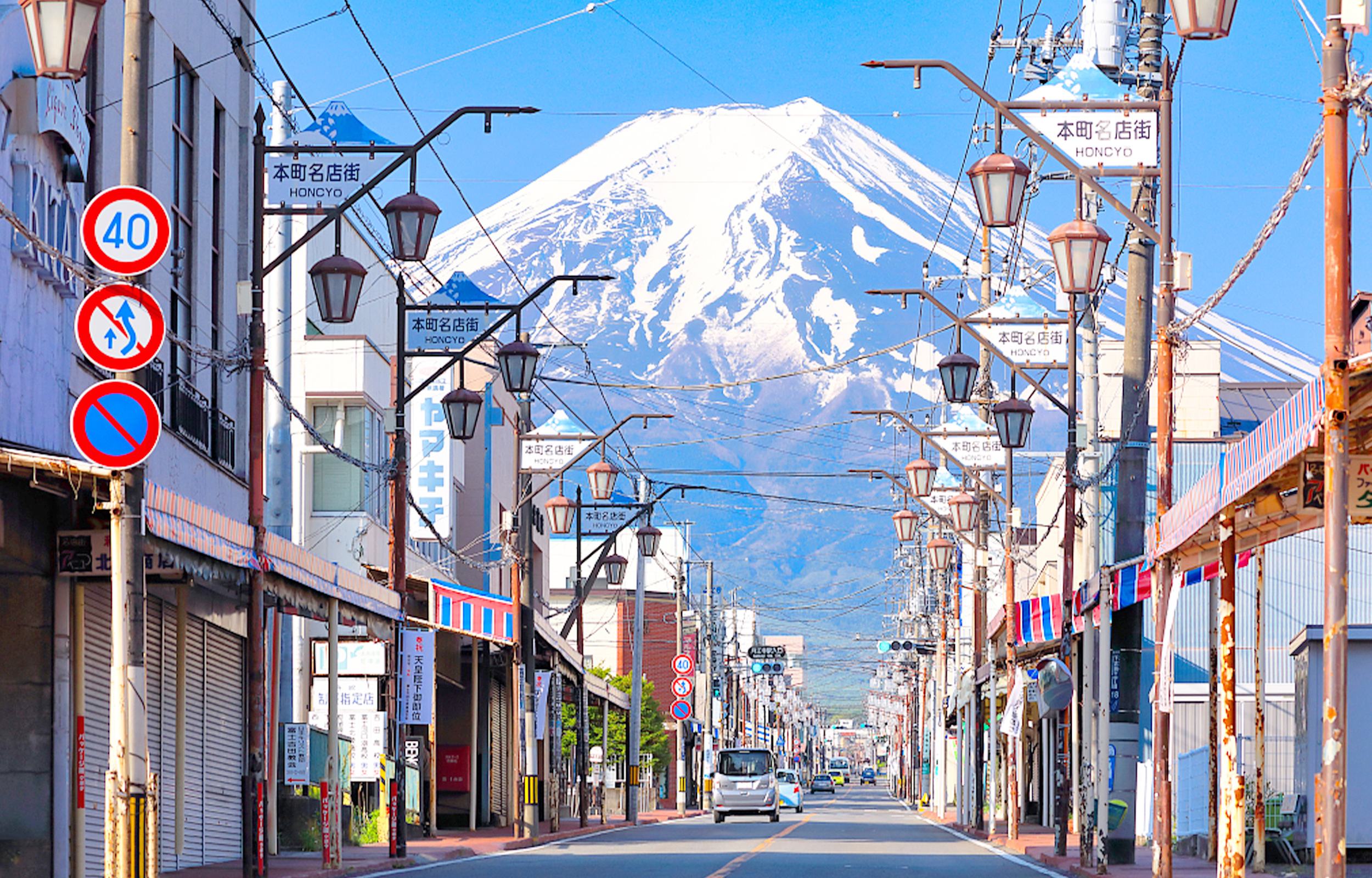 The classic street view of Fujiyoshida City offers a superb photographic angle where the Showa era ambiance meets modern aesthetics. It's achieved by looking at the snow-capped Mount Fuji from the end of the shopping street.
