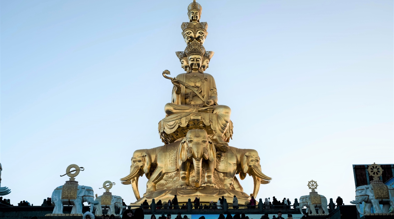 a golden Buddhist statue at the Golden Summit of Mount Emei with many people looking at it