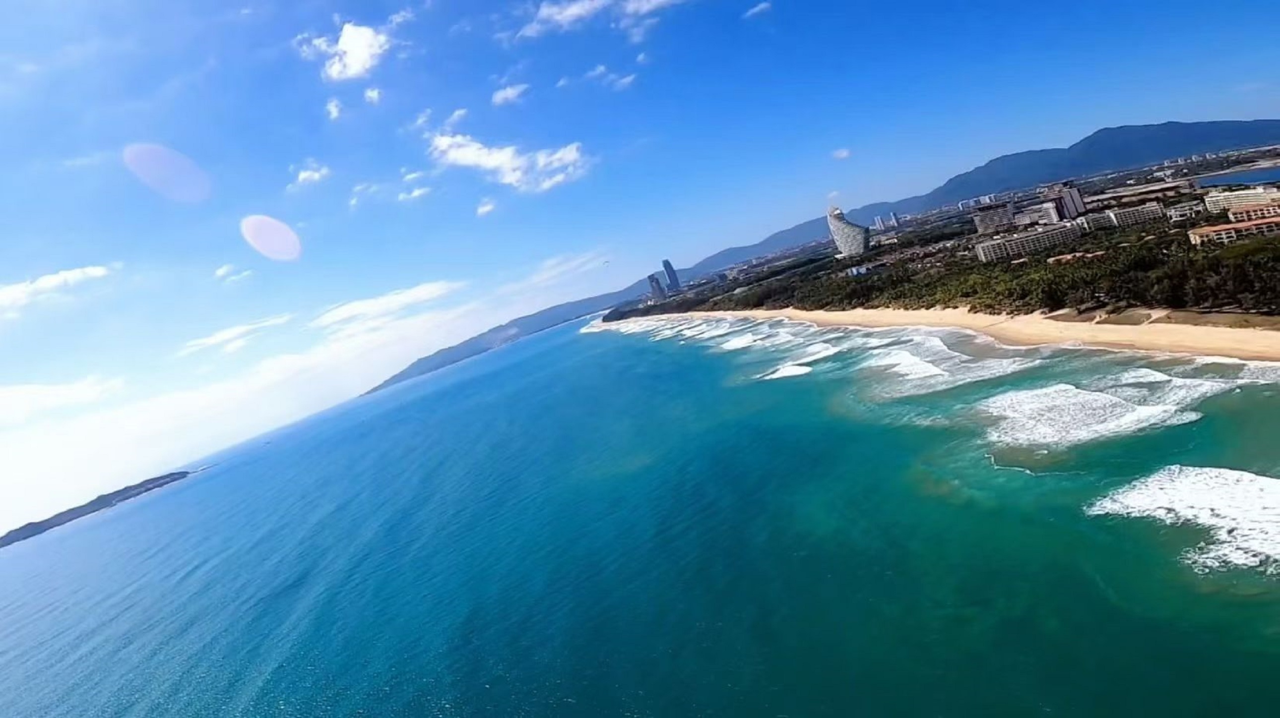 高空裡的海棠灣是塊被上帝調亮的藍綠寶石，浪濤在海面犁出細碎的白痕，沙灘鑲著椰林的深綠邊兒，遠處山巒淡成青灰色剪影
