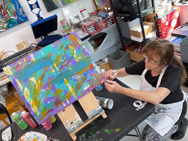 Eyes locked, knife in hand, she's completely immersed in her own world of texture and color