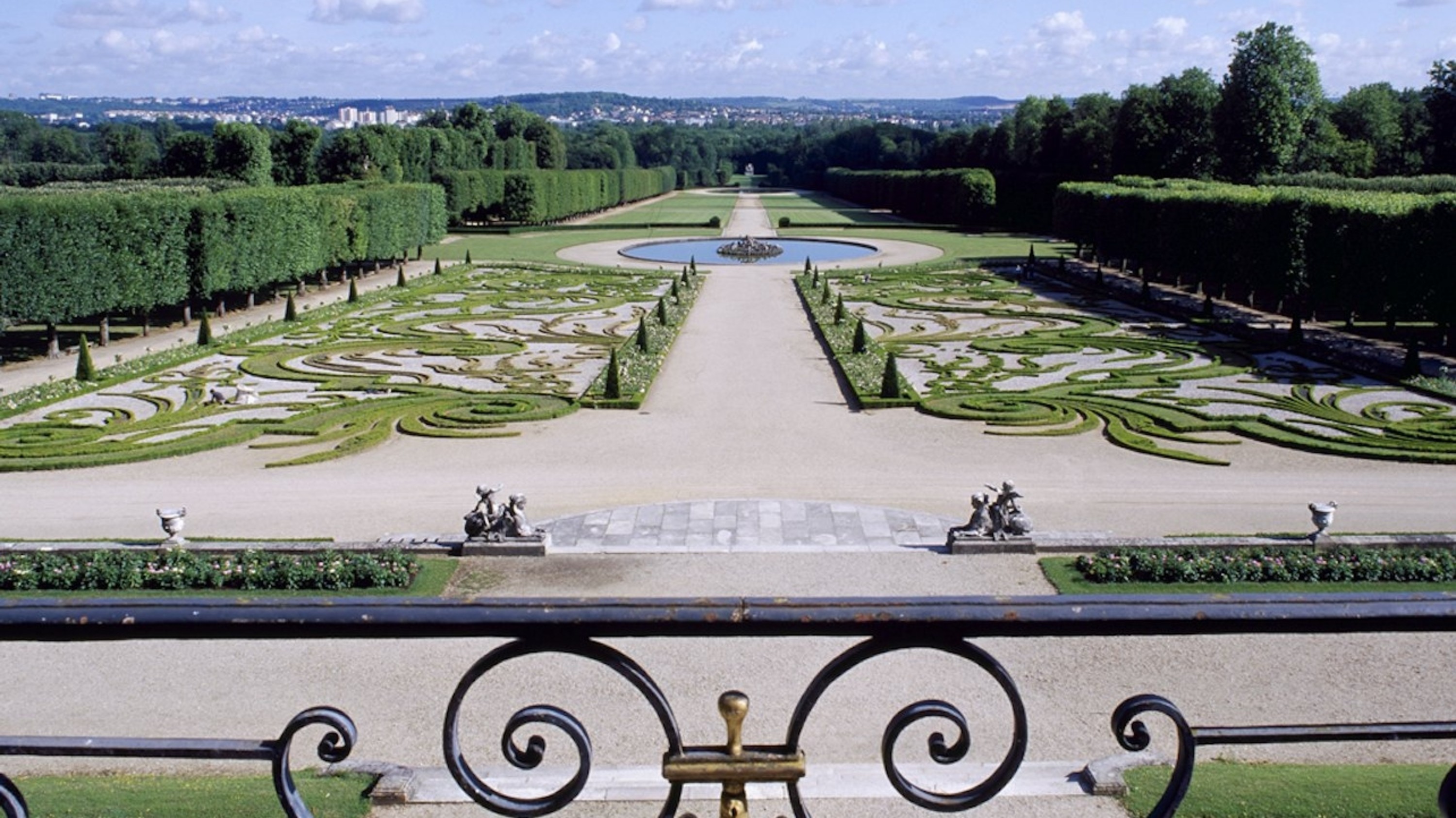 The veranda view reveals lush, formal gardens blooming beneath the soft morning sunlight