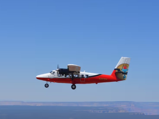 Scenic Papillon airplane flying above Hoover Dam with sparkling Lake Mead glistening beneath afternoon sun
