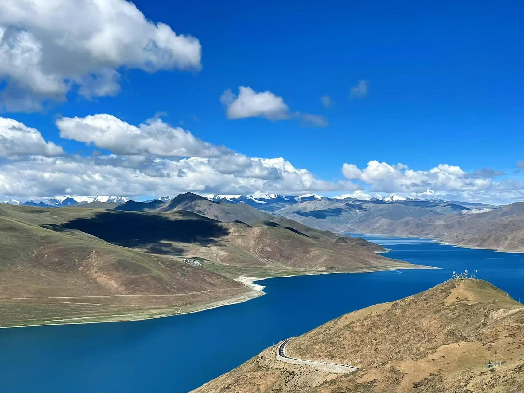 聖湖羊卓雍措湖水湛藍如寶石,蜿蜒鋪展在連綿土黃山巒間。盤山公路沿湖山蜿蜒,遠處雪山連綿,蓬鬆白雲鋪滿晴空,湖山遼闊,盡顯西藏聖湖純淨遼闊之美 聖湖羊卓雍措湖水湛藍如寶石,蜿蜒鋪展在連綿土黃山巒間。盤山公路沿湖山蜿蜒,遠處雪山連綿,蓬鬆白雲鋪滿晴空,湖山遼闊,盡顯西藏聖湖純淨遼闊之美