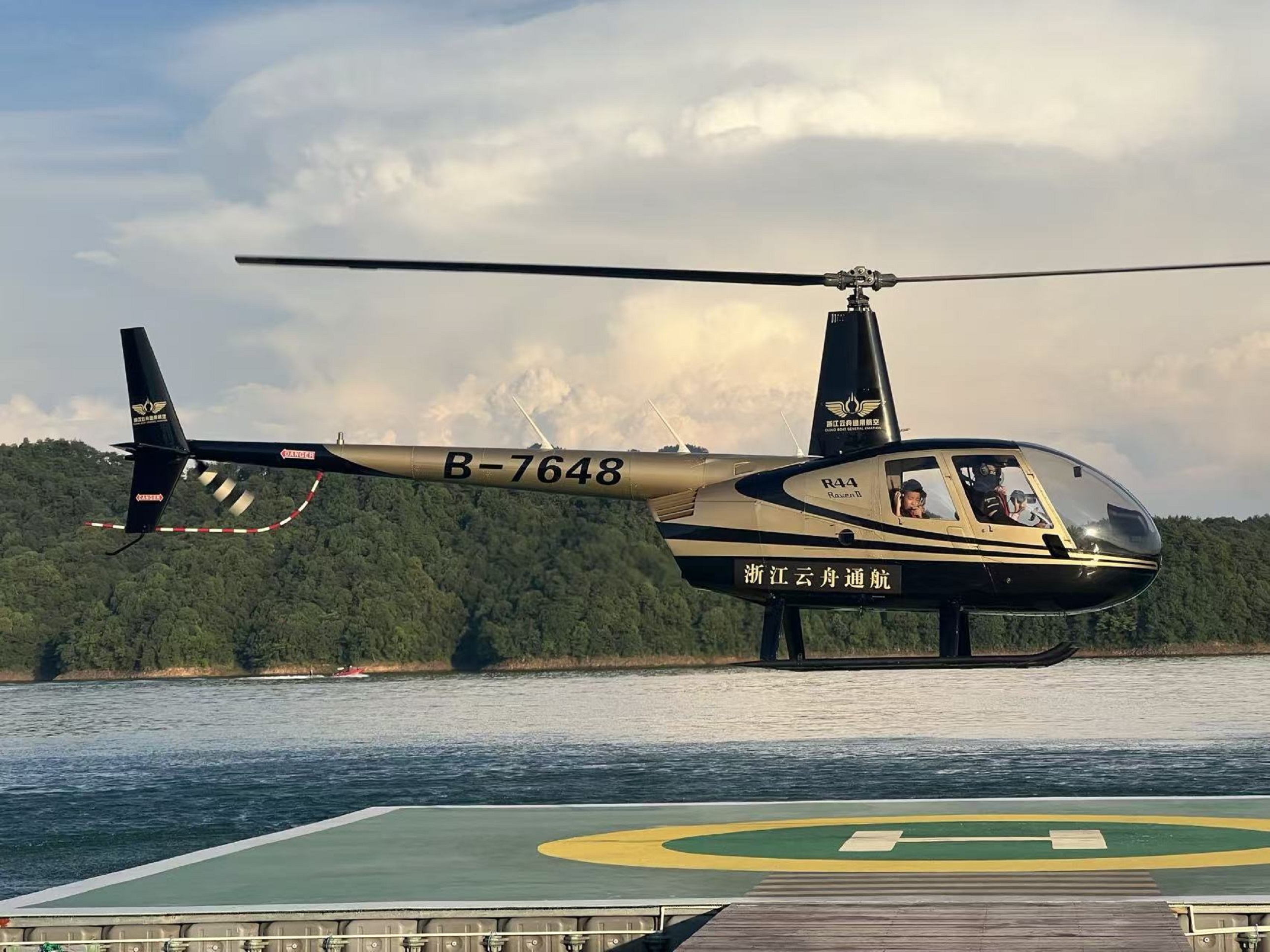 黑金直升機停駐水上停機坪，背景是浩渺湖面與層疊遠山，即將起飛的姿態自帶電影感，輕奢氛圍拉滿，是千島湖獨有的空中出行儀式感
