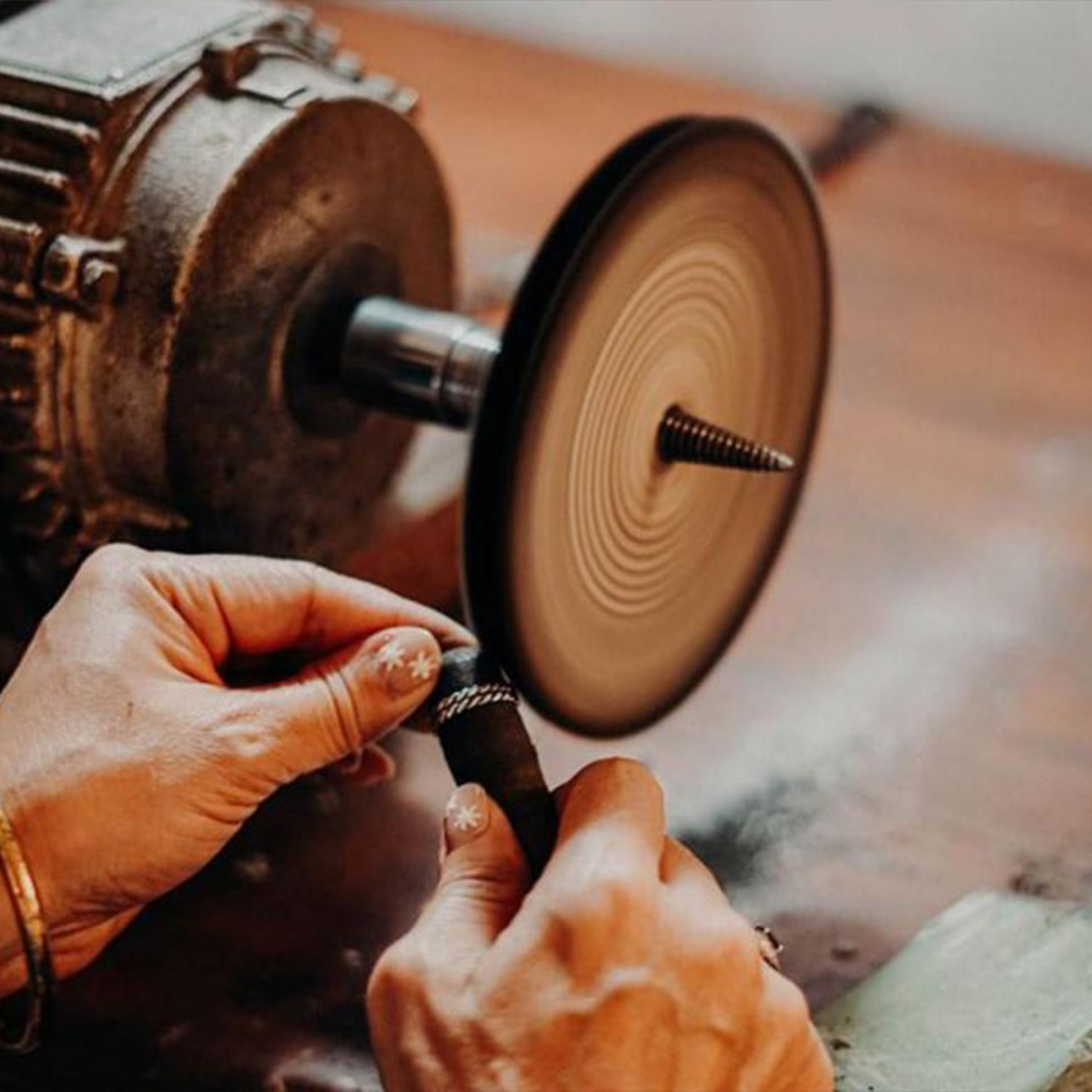A silversmith polishes his work with a machine, producing a smooth shine and beautiful detail.