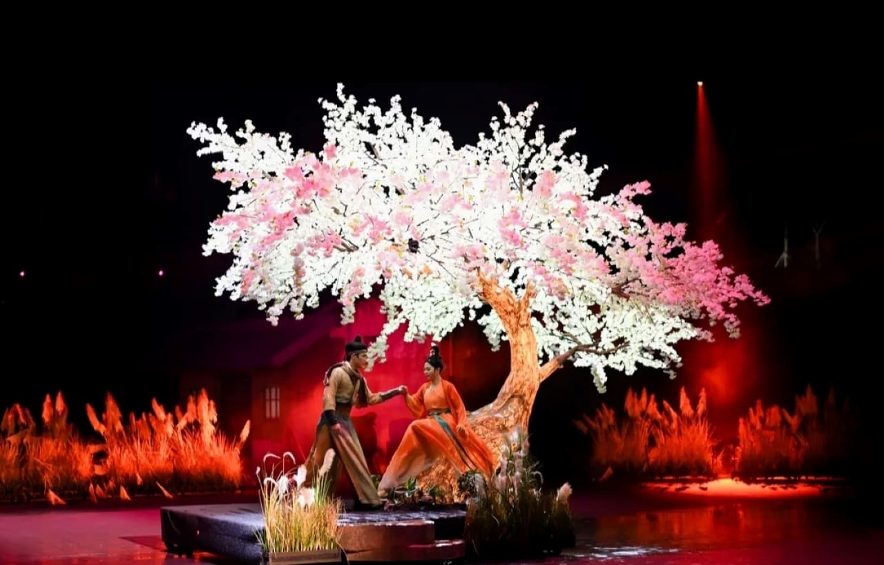 浪漫一幕,男女舞者於繁花盛開的樹下互動。樹影交織、服飾典雅,以詩意場景演繹潮汕故事裡的情感羈絆,借唯美的舞臺佈景與肢體語言,傳遞民俗文化中細膩的人文情懷 浪漫一幕,男女舞者於繁花盛開的樹下互動。樹影交織、服飾典雅,以詩意場景演繹潮汕故事裡的情感羈絆,借唯美的舞臺佈景與肢體語言,傳遞民俗文化中細膩的人文情懷