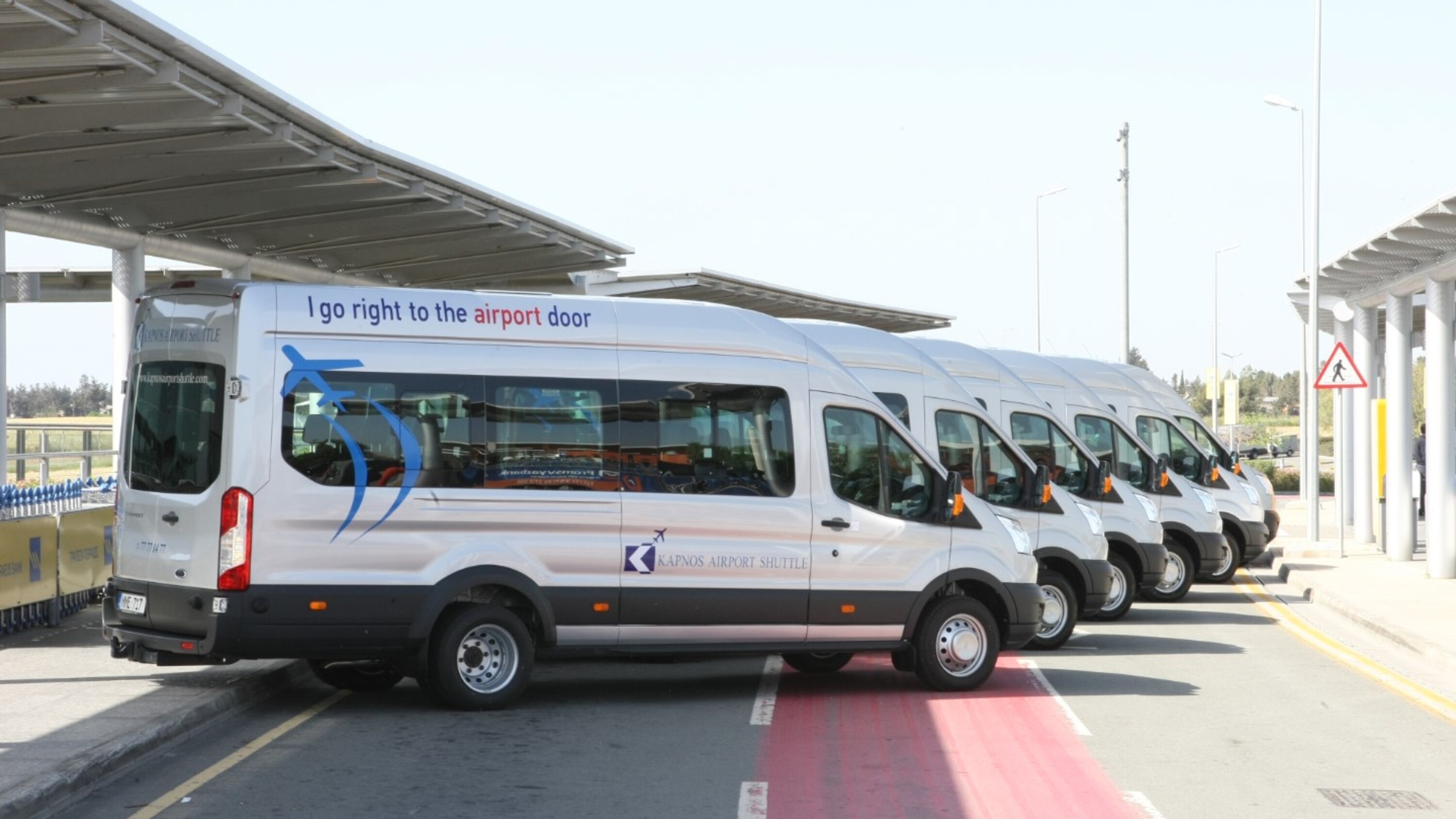 Shuttle buses lined up in a row, ready for passengers at the terminal curb