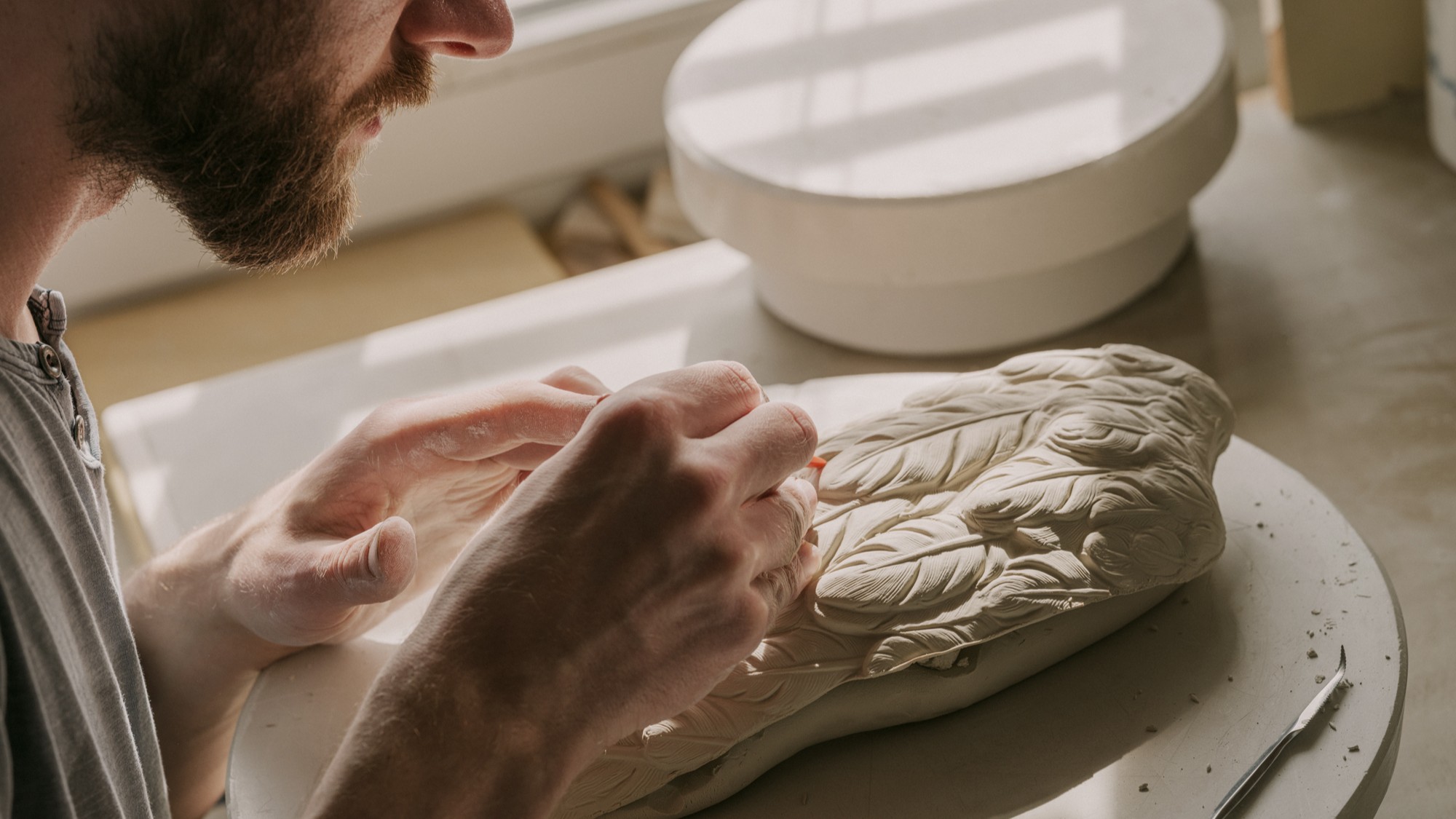 Observe skilled artisans hand-carving intricate porcelain details with remarkable focus and craftsmanship
