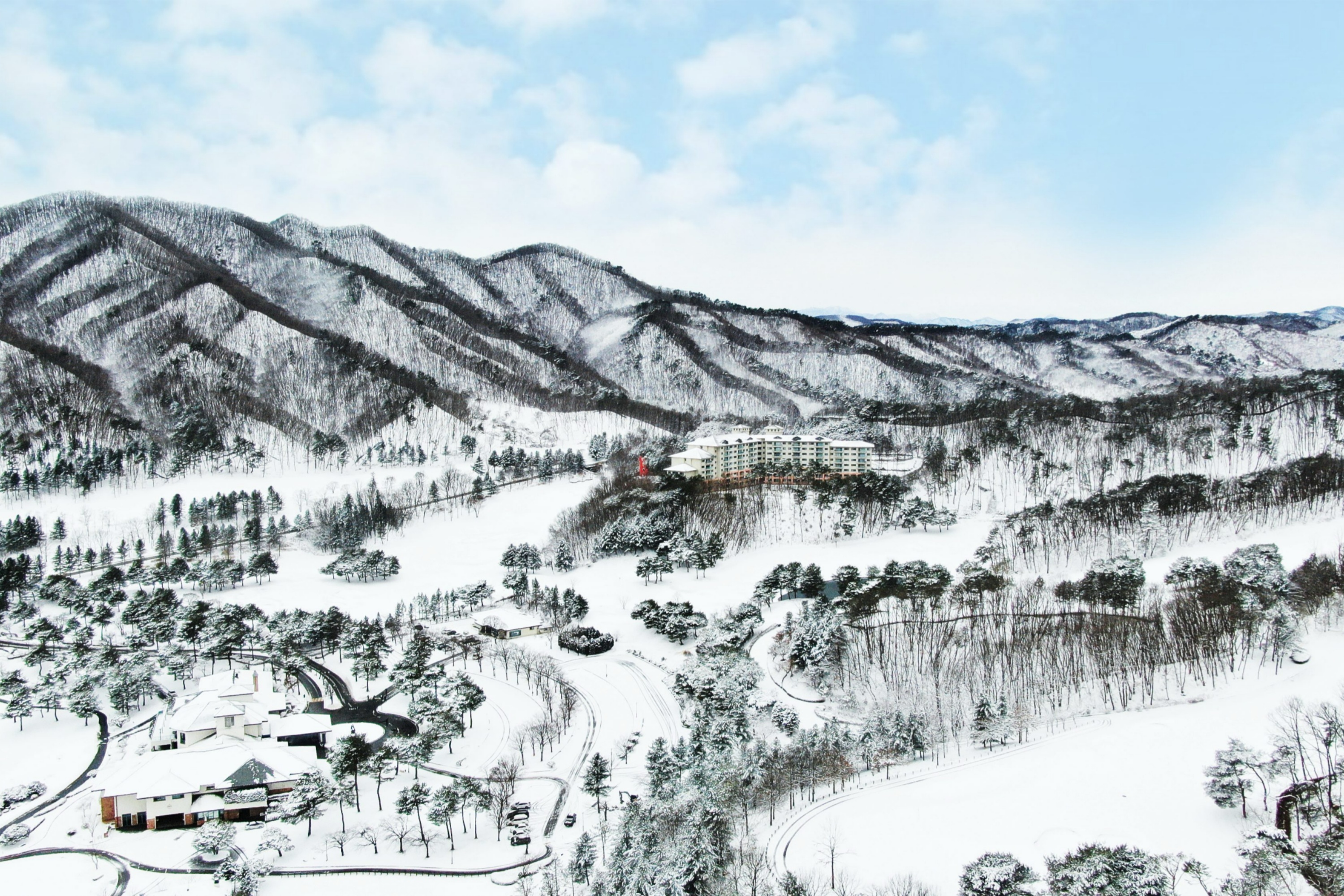 原州橡樹谷度假村的鳥瞰圖——白雪皚皚的山脈、飯店以及韓國雙板滑雪之旅的冬季景觀。 原州橡樹谷度假村的鳥瞰圖——白雪皚皚的山脈、飯店以及韓國雙板滑雪之旅的冬季景觀。