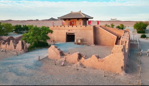 陽關關城遺址的復原建築。畫面中,一座夯土築成的關樓巍然矗立,城門上方覆以傳統中式瓦頂,簷下飄揚著紅旗,增添了歷史的厚重感與視覺衝擊力。關樓周圍保留了部分殘破的城牆遺蹟,沙土路面與荒漠背景相呼應,僅有的幾棵綠樹點綴其間,凸顯出絲路關隘“孤城遙望玉門關”的蒼涼意境。 陽關關城遺址的復原建築。畫面中,一座夯土築成的關樓巍然矗立,城門上方覆以傳統中式瓦頂,簷下飄揚著紅旗,增添了歷史的厚重感與視覺衝擊力。關樓周圍保留了部分殘破的城牆遺蹟,沙土路面與荒漠背景相呼應,僅有的幾棵綠樹點綴其間,凸顯出絲路關隘“孤城遙望玉門關”的蒼涼意境。