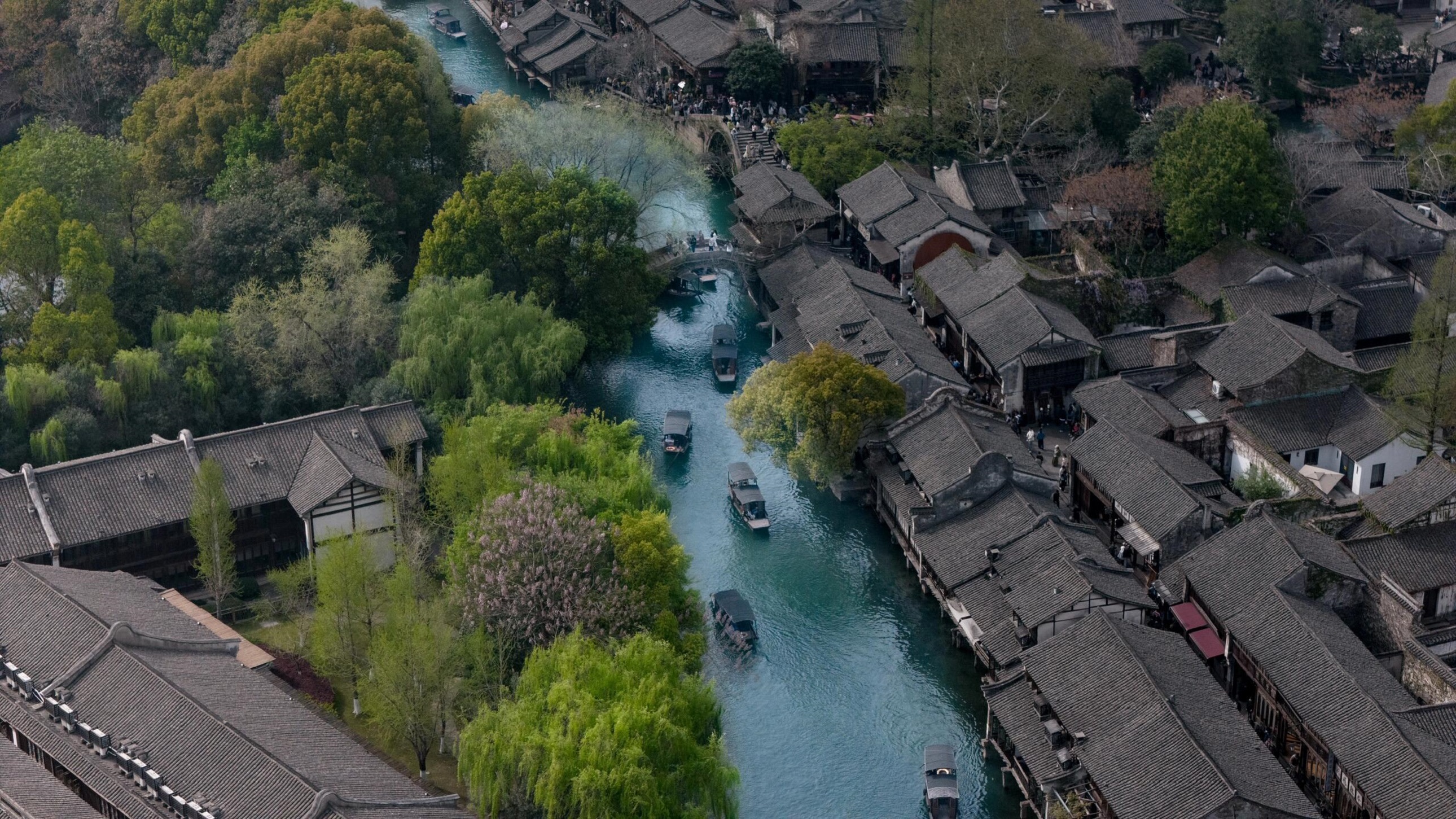 航拍視角下的烏鎮全景！河道如碧帶穿鎮而過，青瓦屋舍錯落有致，綠樹環繞間，千年水鄉的格局與詩意一覽無餘