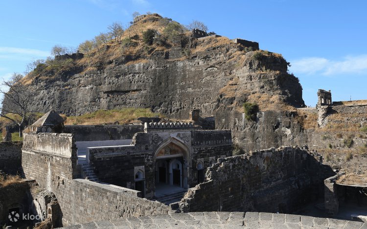 Photograph of Daulatabad Fort (formerly Devagiri Fort) in Aurangabad, Maharashtra showing the massive volcanic rock fort rising 200 meters high, with the spiral staircase entrance, moat, and medieval fortifications visible, captioned as the capital of the Yadava dynasty